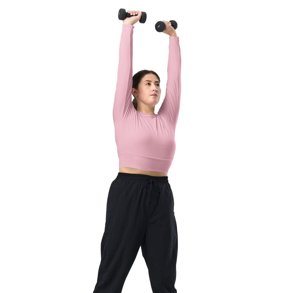 Black dumbbells with textured grips shown alongside a women’s light pink long sleeve performance crop top for workouts