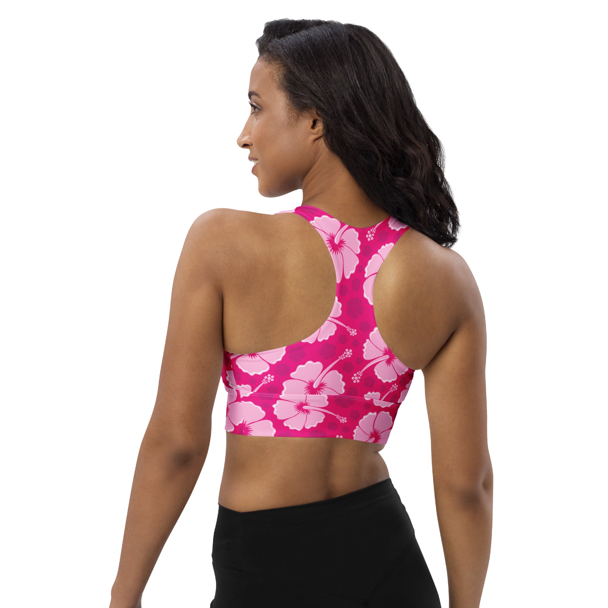 A vibrant pink womens longline sports bra with bold hibiscus flower pattern buttery soft recycled material