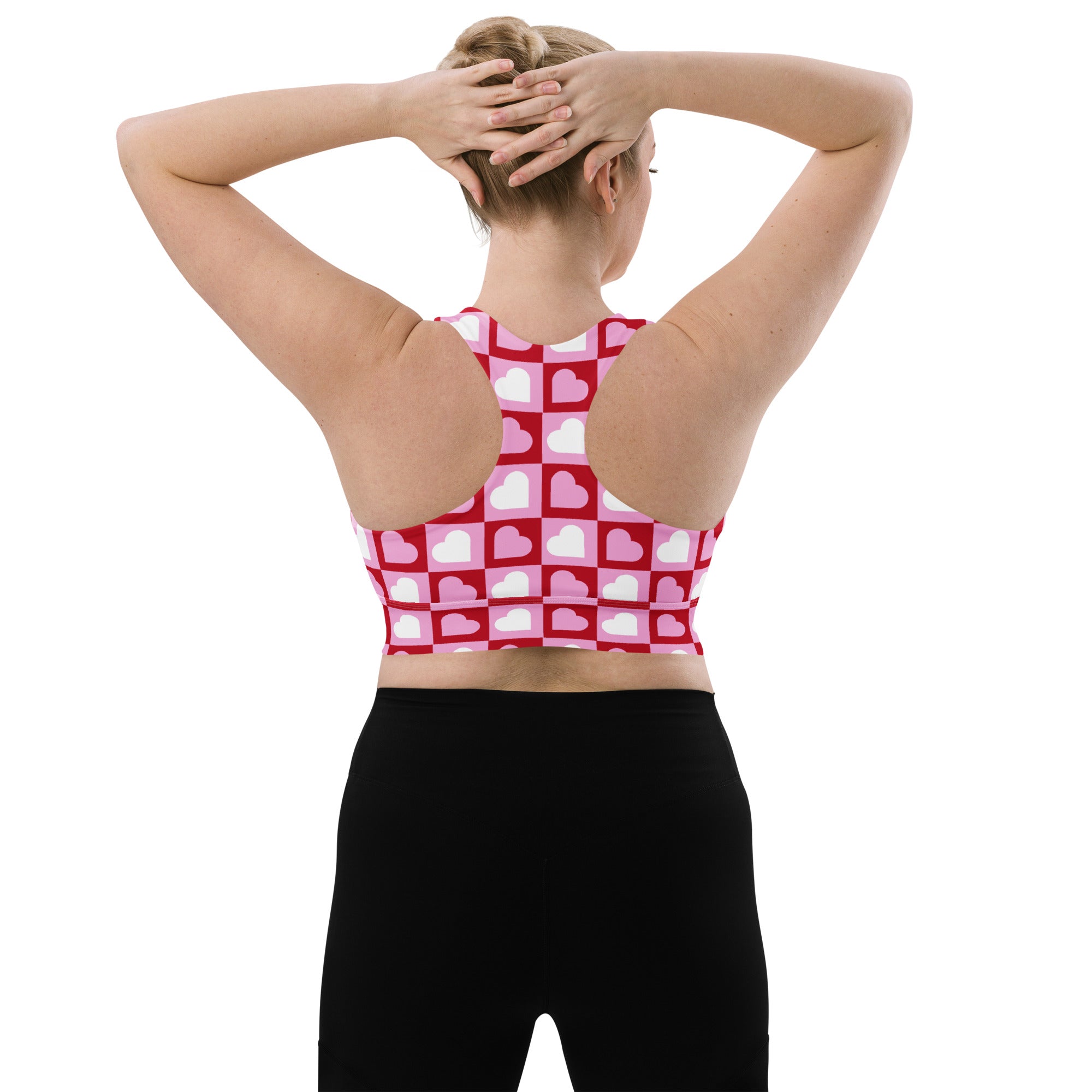 Women’s longline sports bra with pink and white heart print grid design made from buttery soft recycled fabric