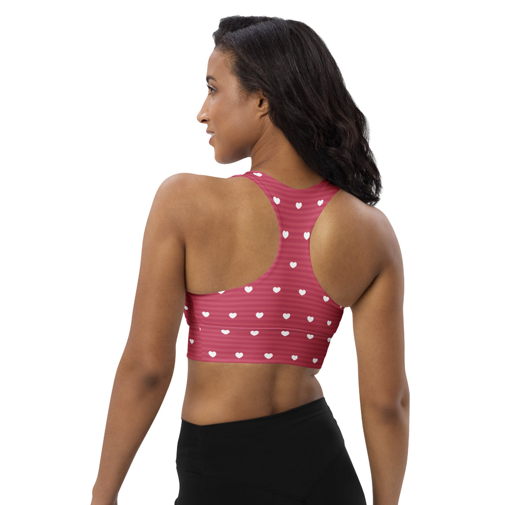 Women’s pink longline sports bra with white heart patterns and stripes made from buttery soft recycled fabric for high support