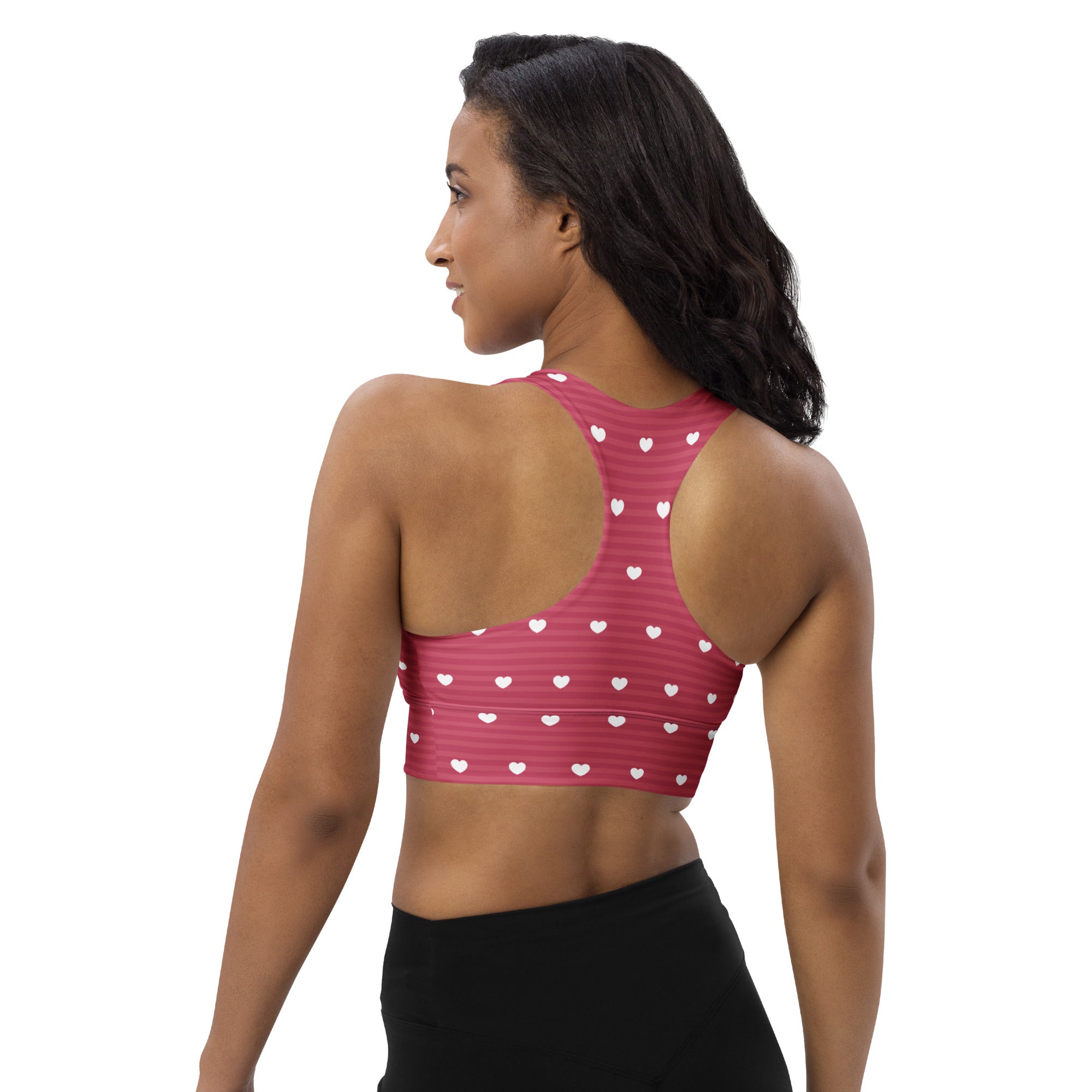 Women’s pink longline sports bra with white heart patterns and stripes made from buttery soft recycled fabric for high support