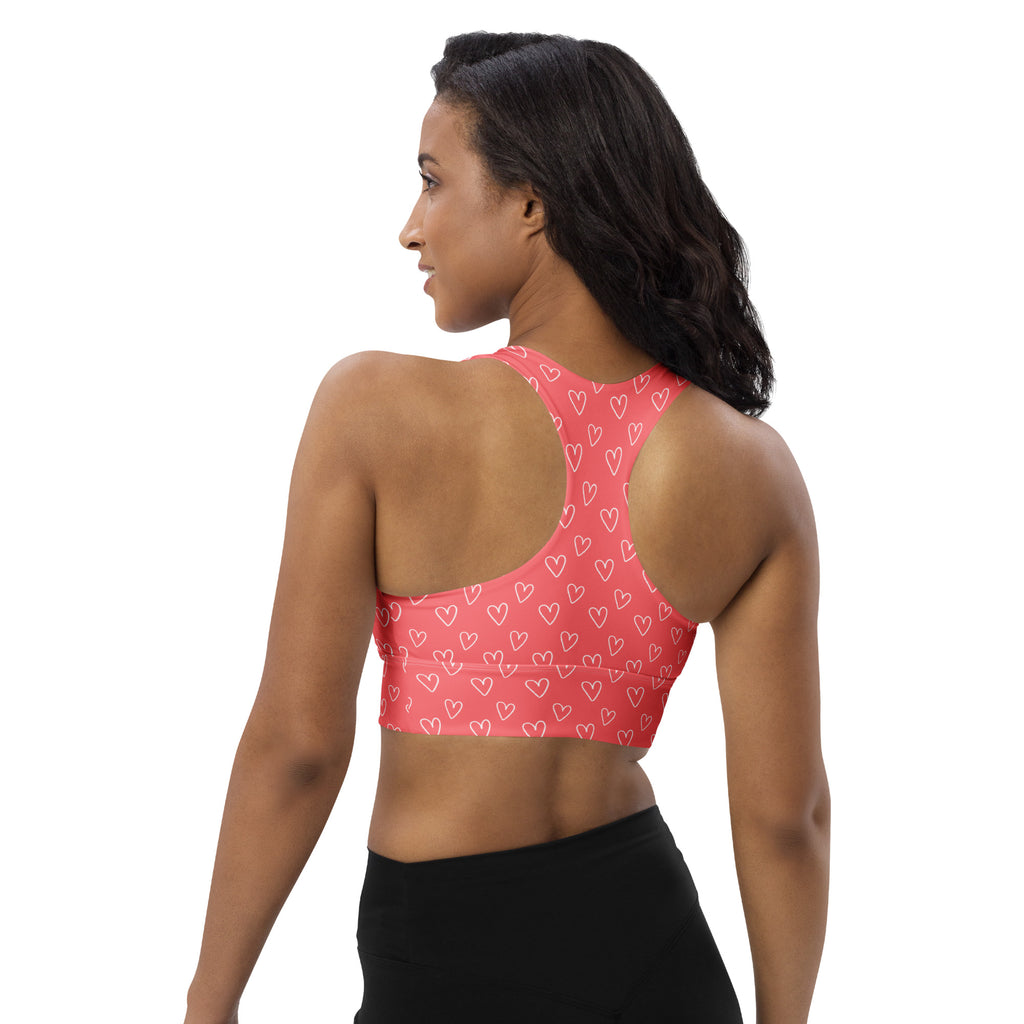 A coral pink longline sports bra with white heart pattern made of buttery soft recycled fabric for high intensity support
