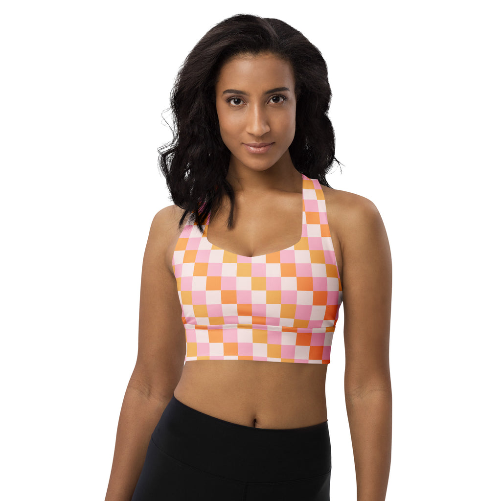 A vibrant pink and peach checkered buttery soft recycled longline sports bra with halter neckline and high intensity support