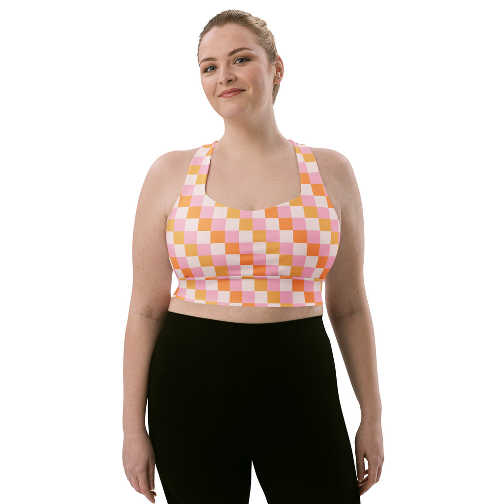 A plus-size woman wears a pink and peach checkered buttery soft recycled sports bra with high intensity support