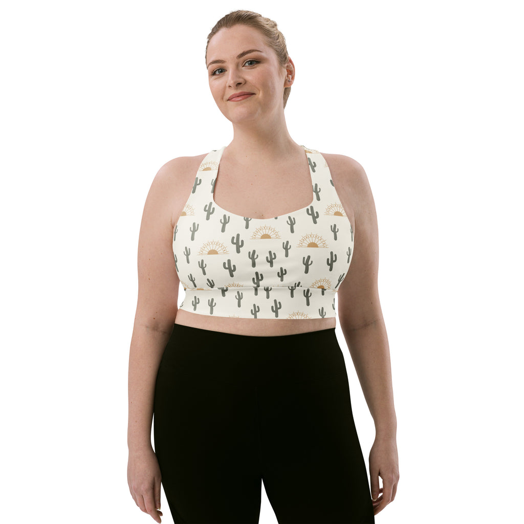 Cream-colored women’s longline sports bra with black cactus and gold sun print, buttery soft recycled fabric, high support