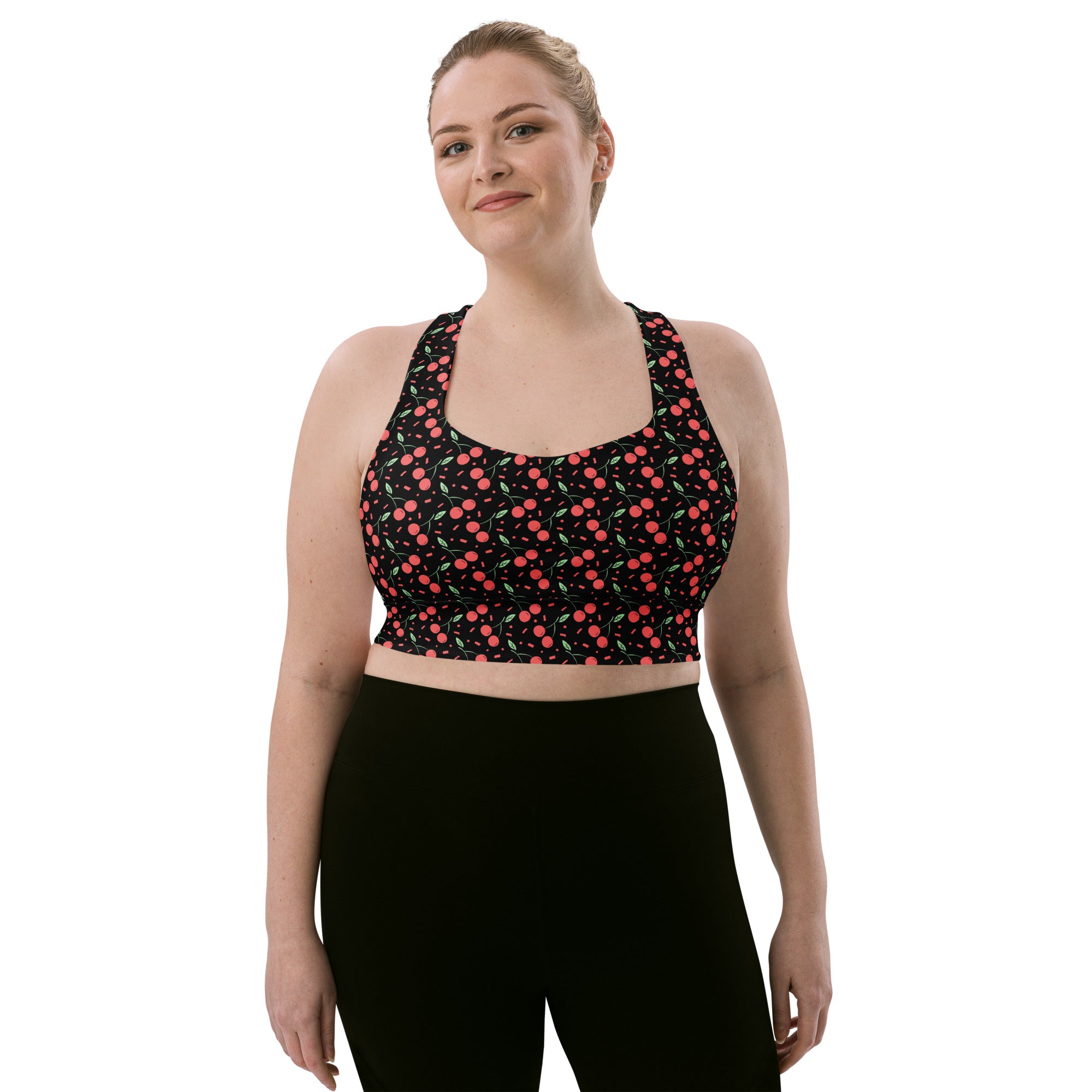 Women’s black recycled longline sports bra with playful pink and light green cherry pattern for high intensity support