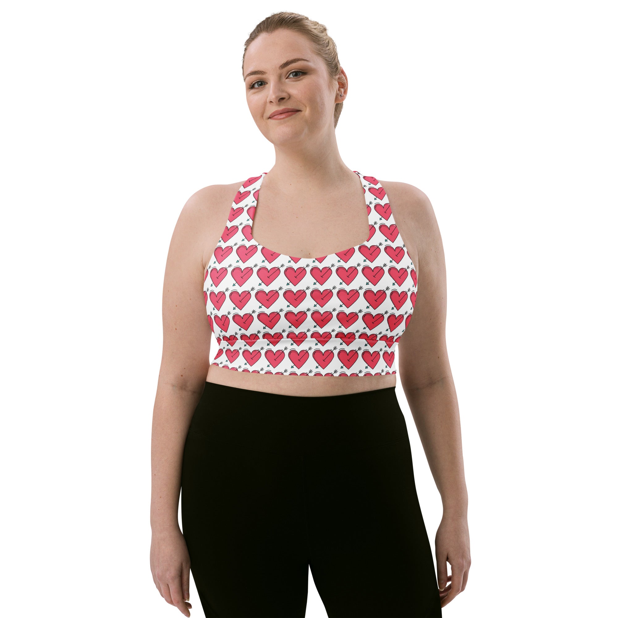 White longline sports bra with pink heart and black arrow pattern made from buttery soft recycled fabric for high intensity support