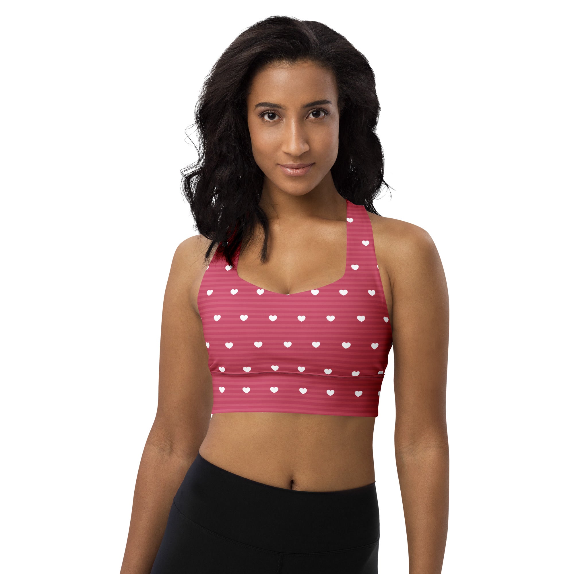 Women’s pink longline sports bra with white heart patterns and stripes made from buttery soft recycled fabric for high support