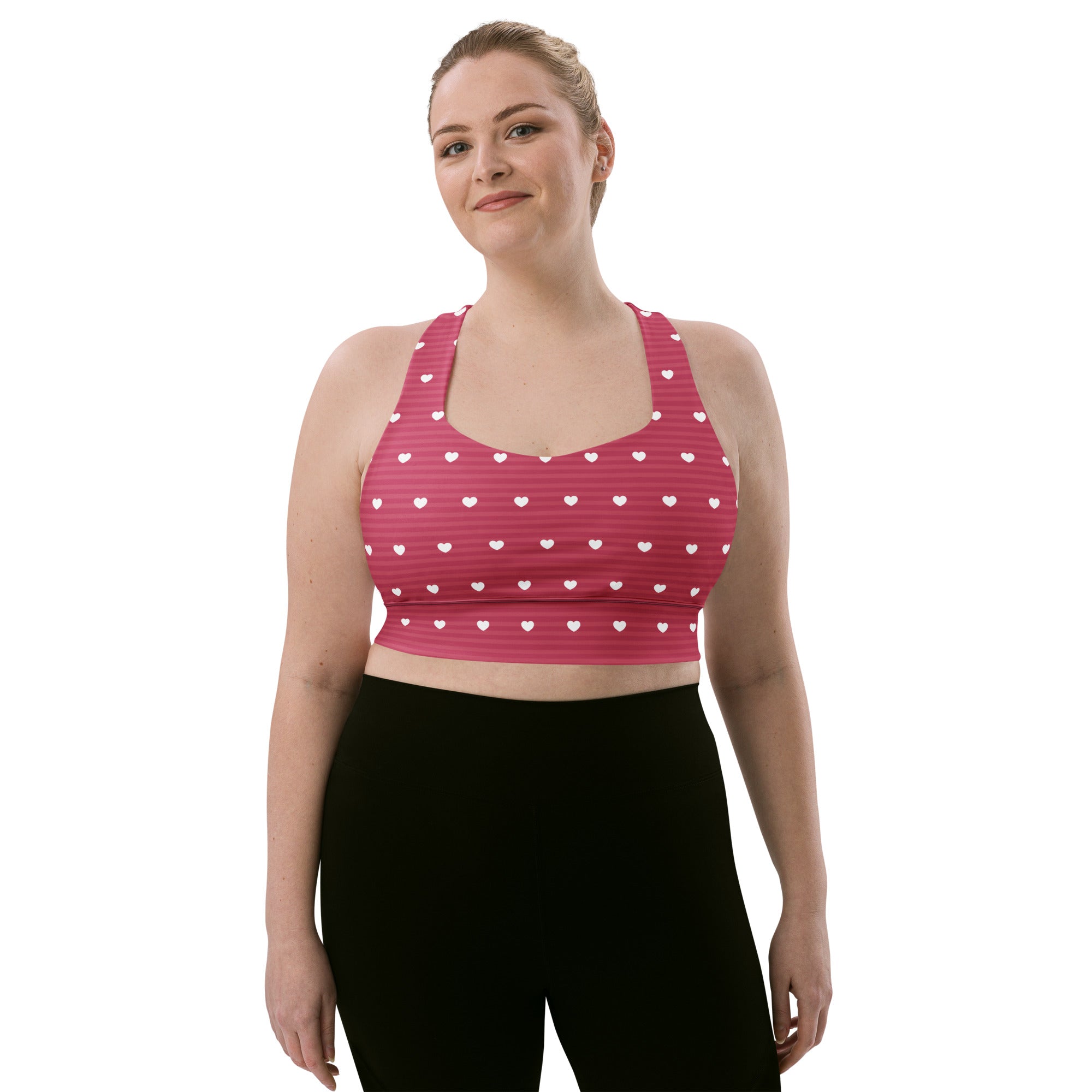 Pink longline sports bra with white heart patterns and stripes made from buttery soft recycled fabric for high intensity support