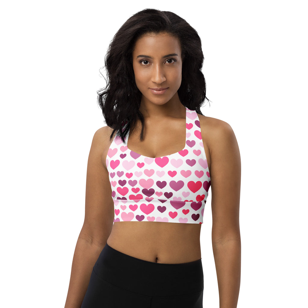 A white longline sports bra with pink and purple heart print made from buttery soft recycled fabric for high intensity support