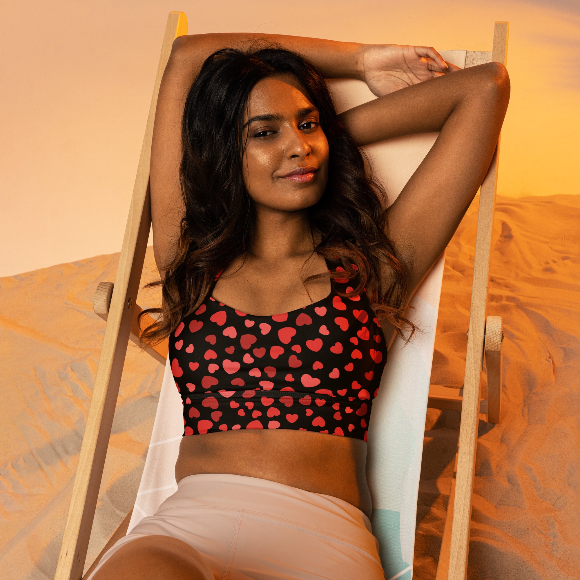 Black longline sports bra with red heart pattern made from buttery soft recycled fabric for high intensity support