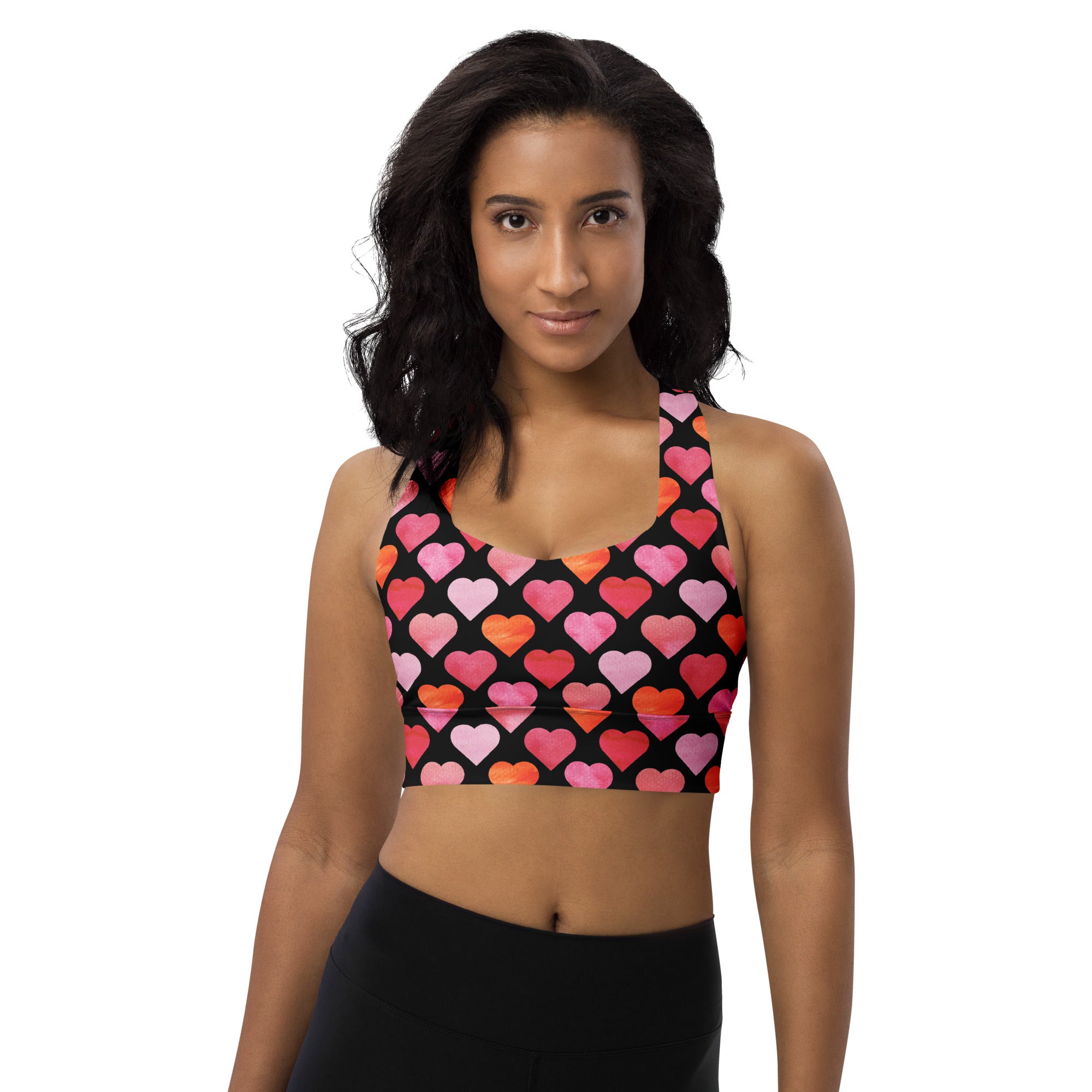 Women’s black recycled longline sports bra with vibrant pink and orange heart print, high intensity support, and quick dry