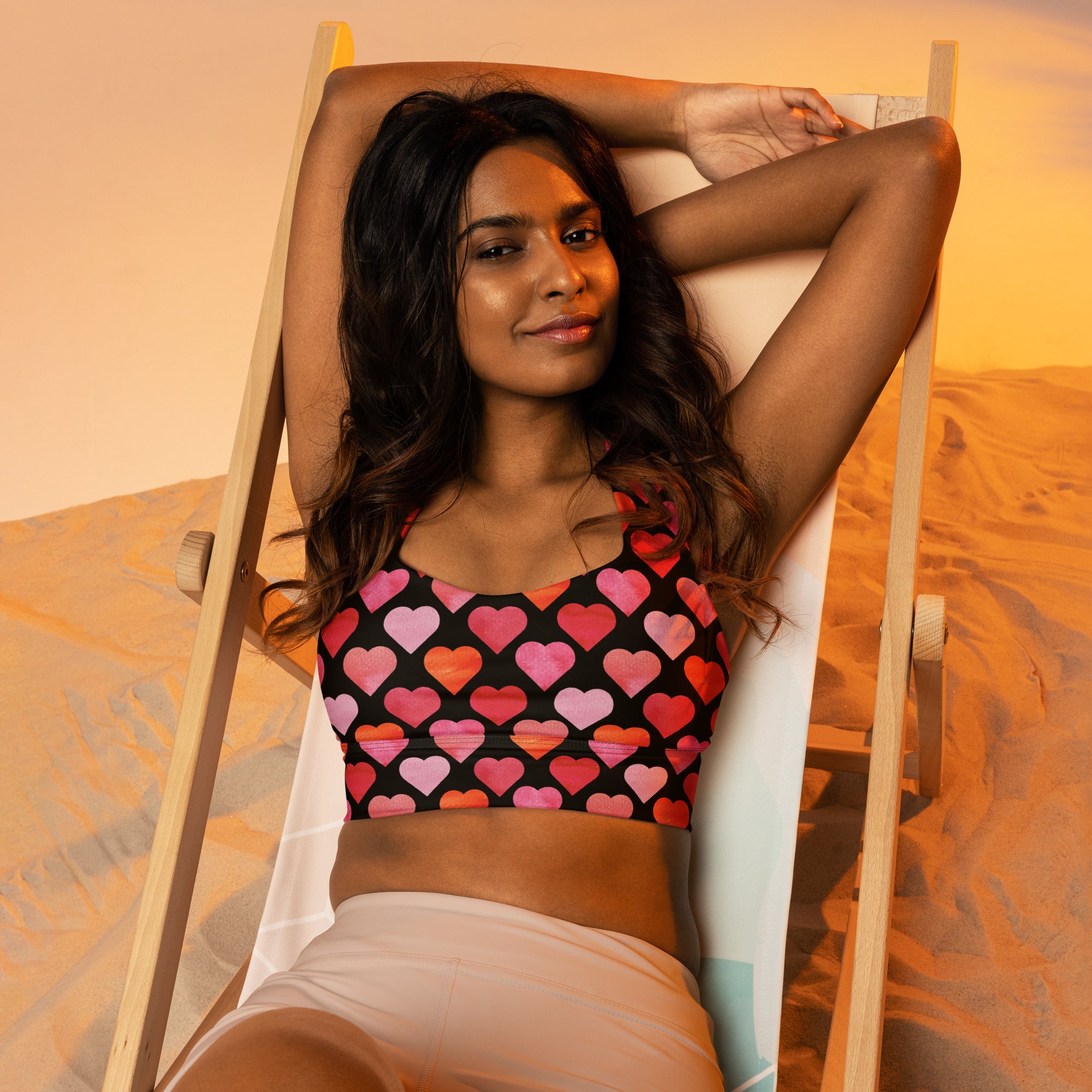 Black longline sports bra with vibrant pink red and orange heart pattern made from buttery soft recycled fabric