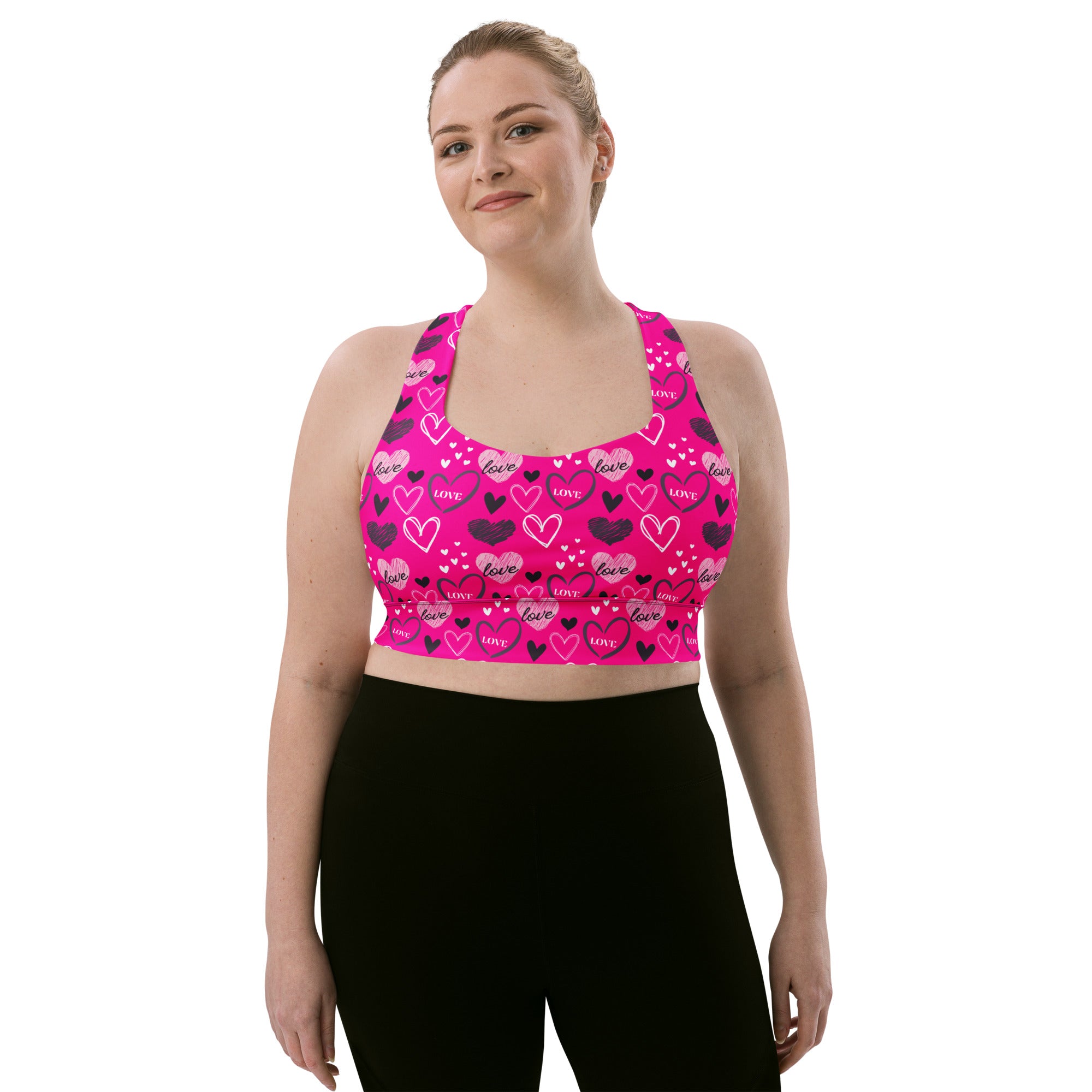 Vibrant pink longline sports bra with playful black and white love heart pattern made from buttery soft recycled fabric