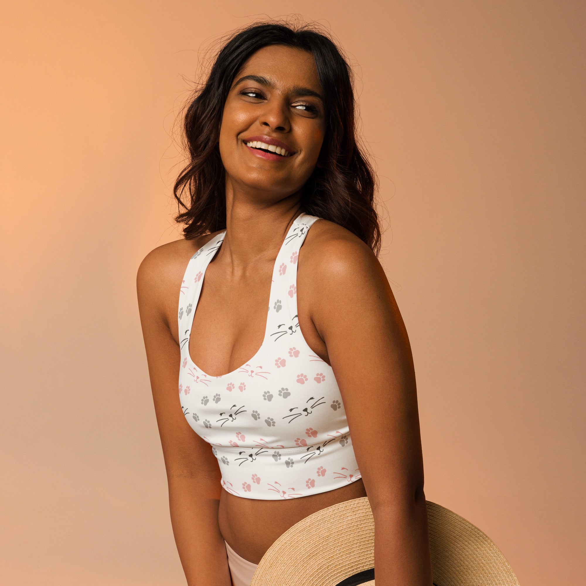 Women’s white longline sports bra with playful pink and gray cat face and paw prints made from buttery soft recycled fabric