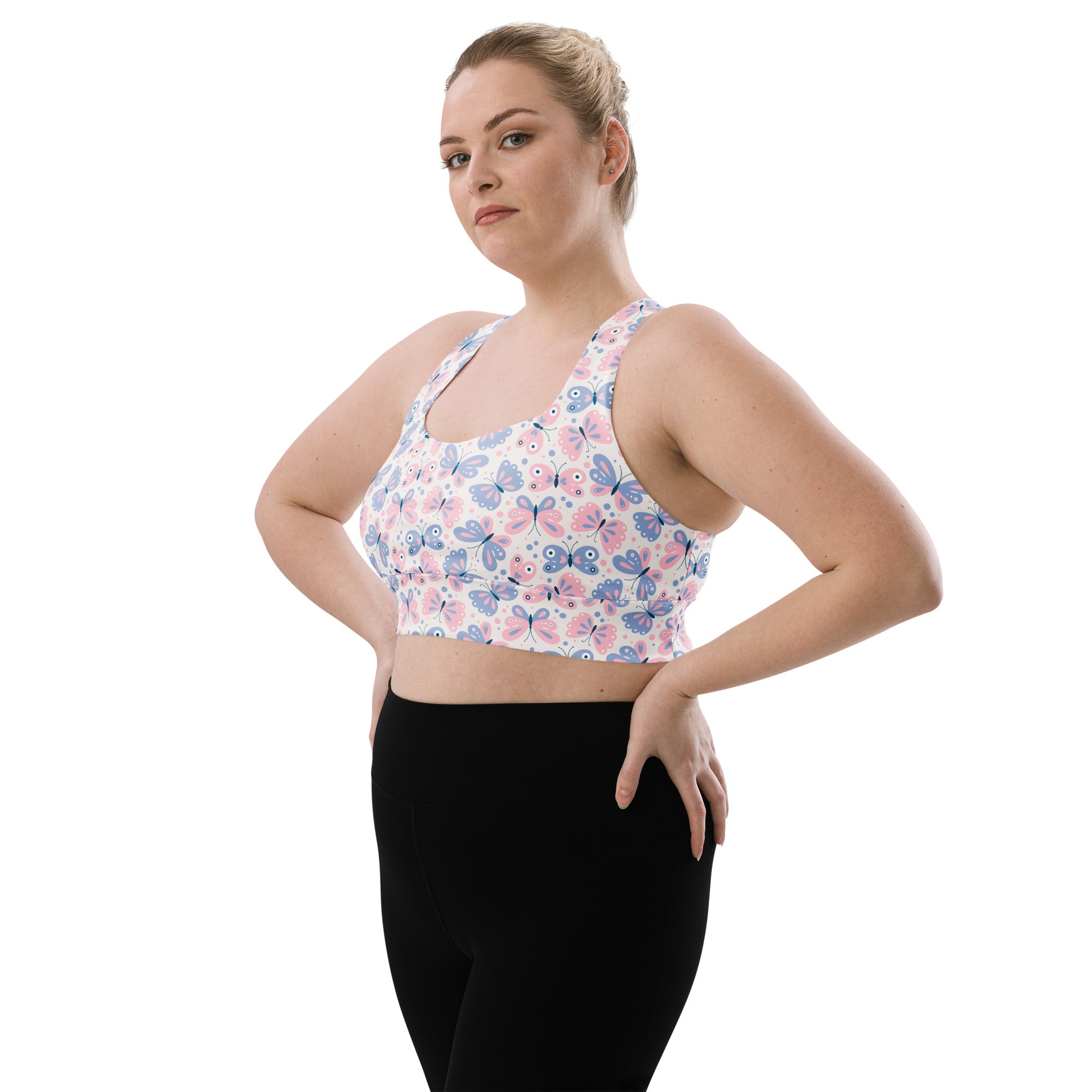 A white women’s longline sports bra with pink and blue butterfly print made from buttery soft recycled fabric