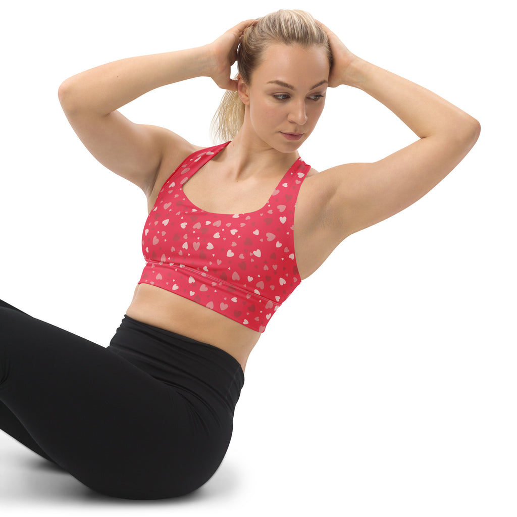 A vibrant red women’s longline sports bra with white and pink heart pattern buttery soft recycled fabric