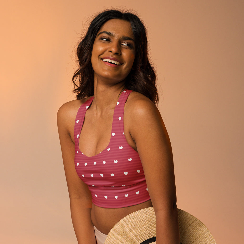 Women’s pink sports bra with white heart patterns buttery soft recycled fabric high intensity support and upf 50+
