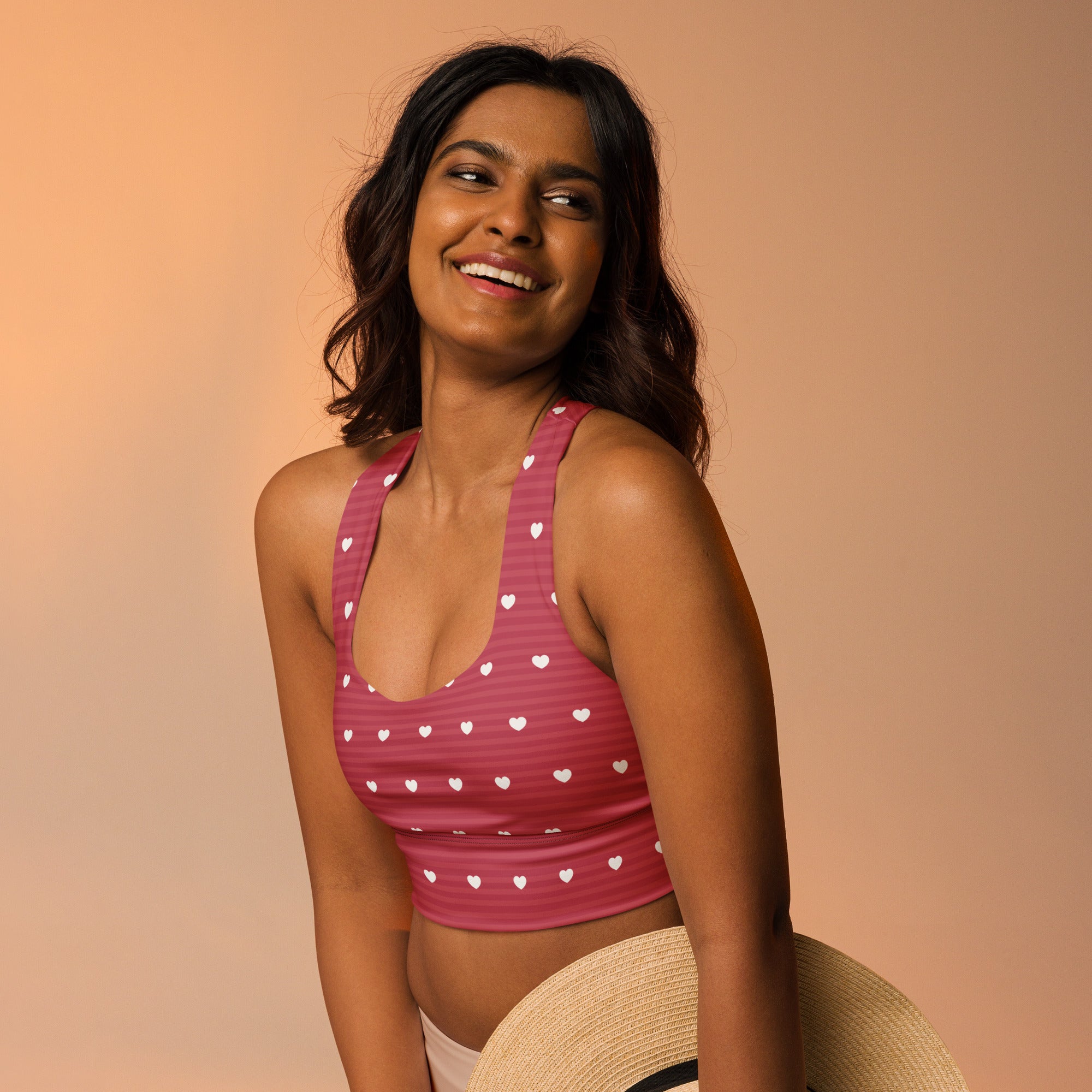 Women’s pink sports bra with white heart patterns buttery soft recycled fabric high intensity support and upf 50+