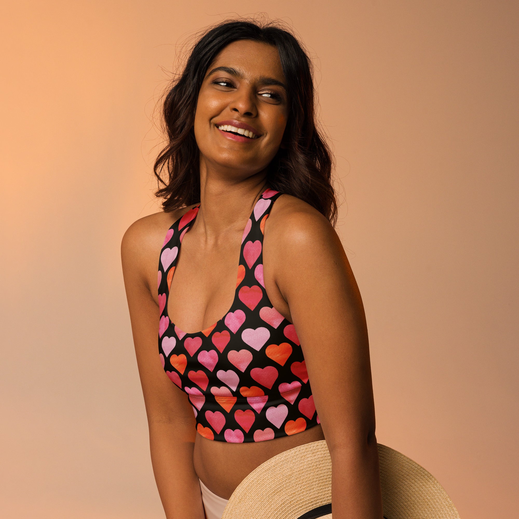 Black halter top sports bra with vibrant pink red orange heart print made from buttery soft recycled fabric