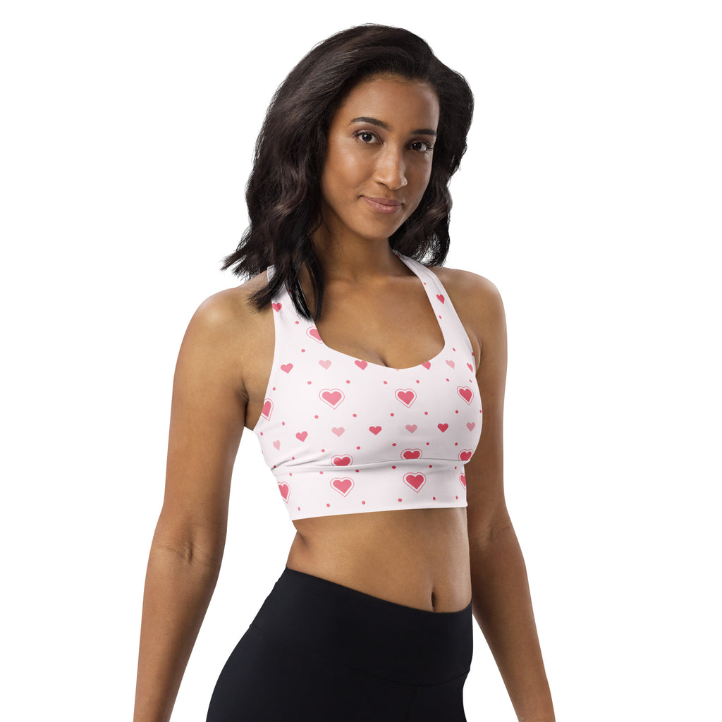 White longline sports bra with pink heart pattern, buttery soft recycled fabric, high intensity support, and quick dry
