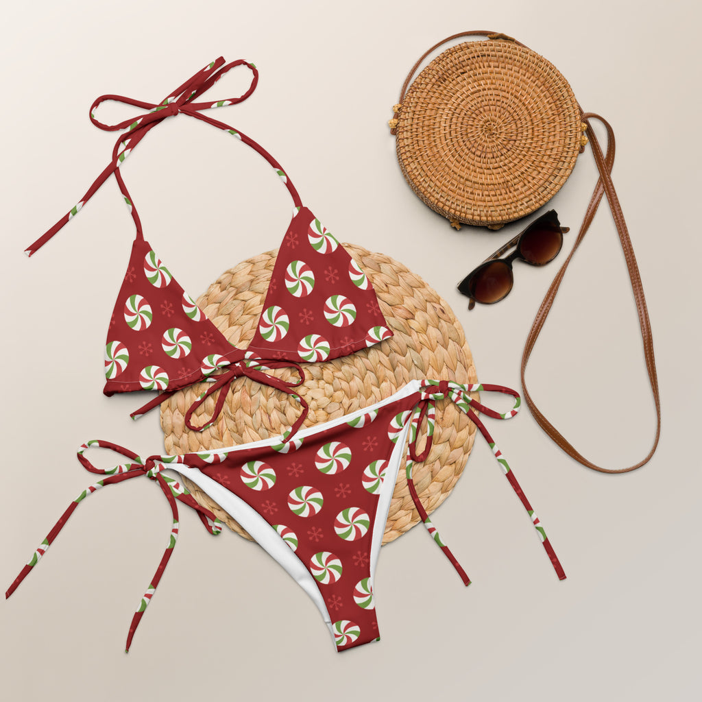 Women’s red peppermint candy buttery soft recycled string bikini with red and white candy cane pattern and green accents