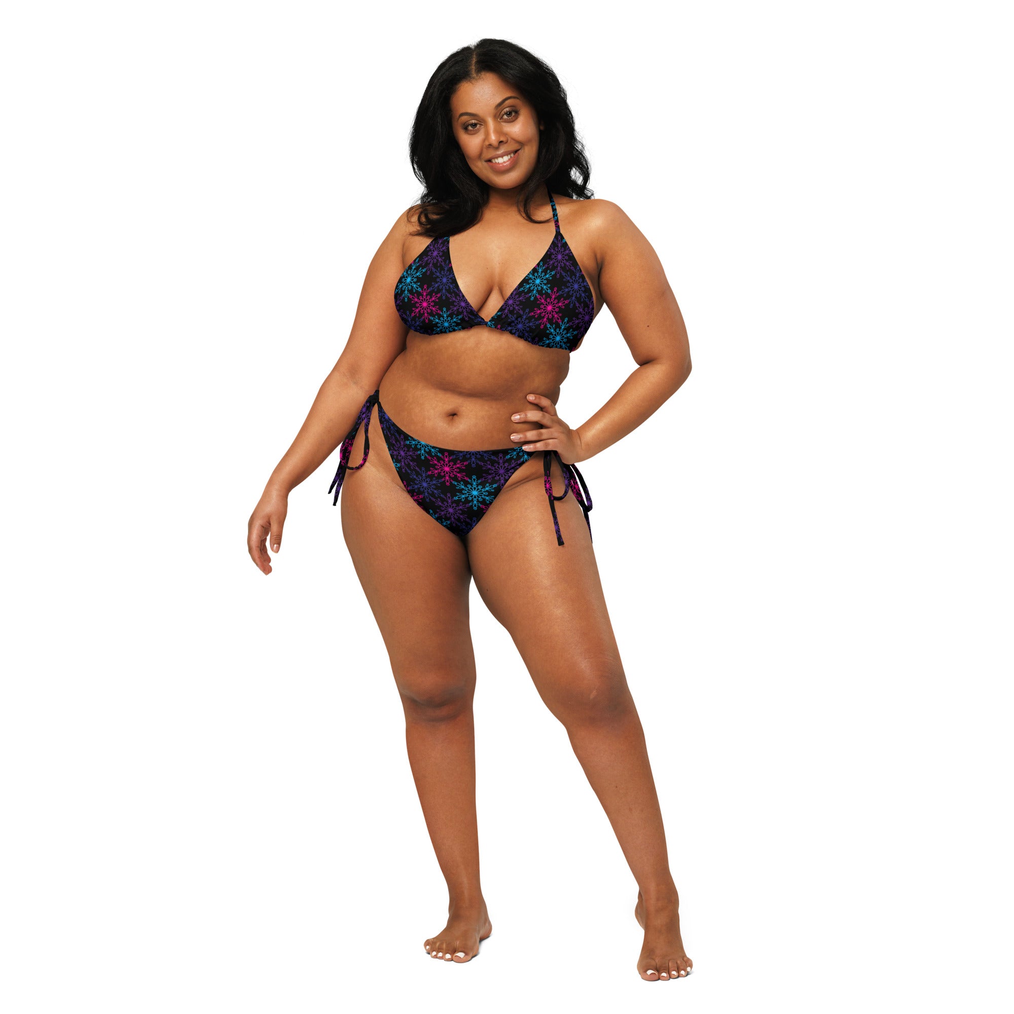 A plus-size woman models a dark navy neon snowflake recycled string bikini with side ties and UPF 50 plus protection