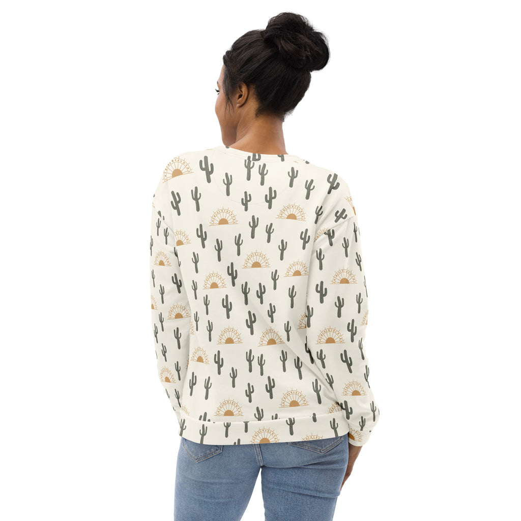 A cream-colored cactus desert sunrise sweatshirt with black cactus and gold sunburst pattern and brushed fleece fabric