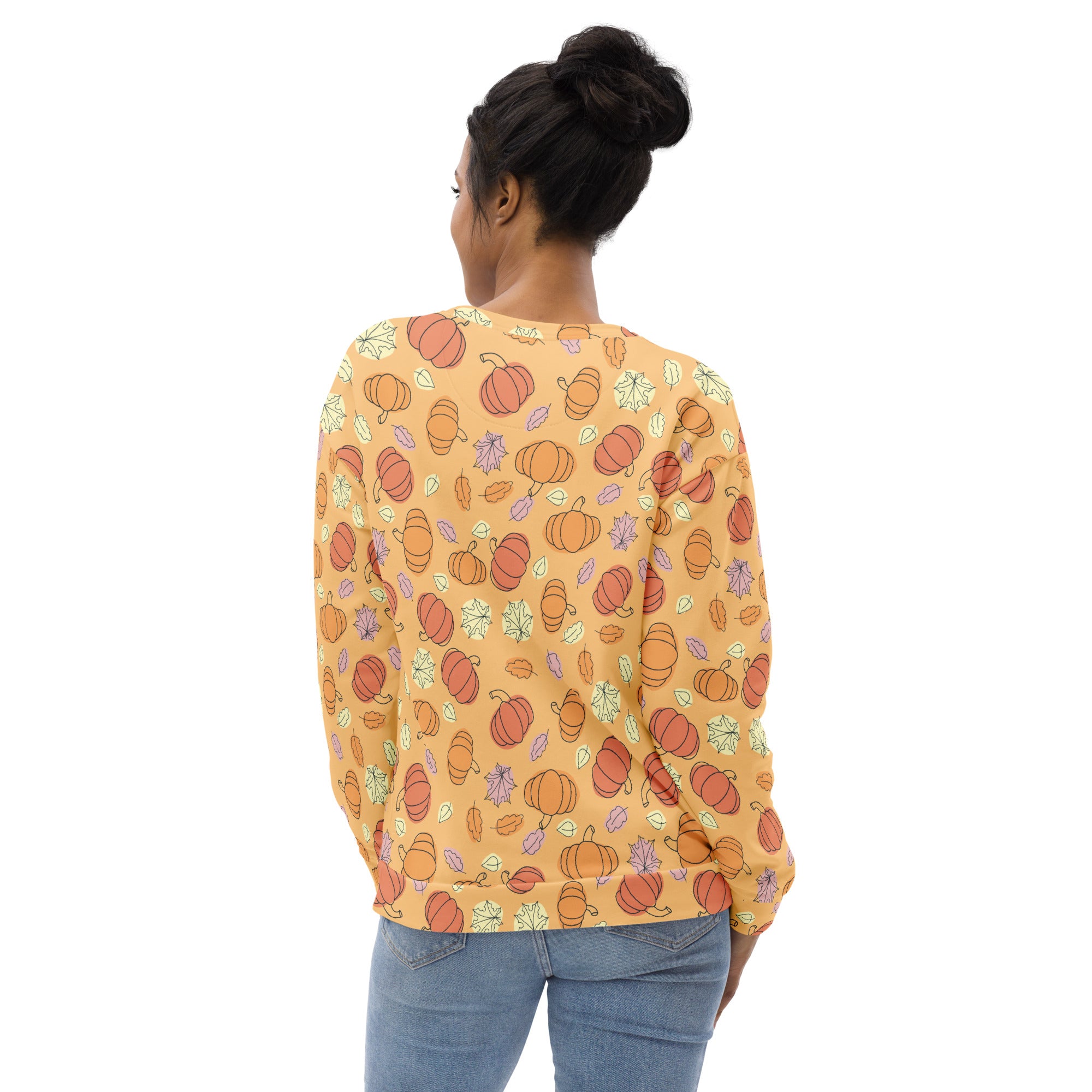 A soft peach long-sleeved sweatshirt with orange pumpkins and multicolored autumn leaves featuring brushed fleece