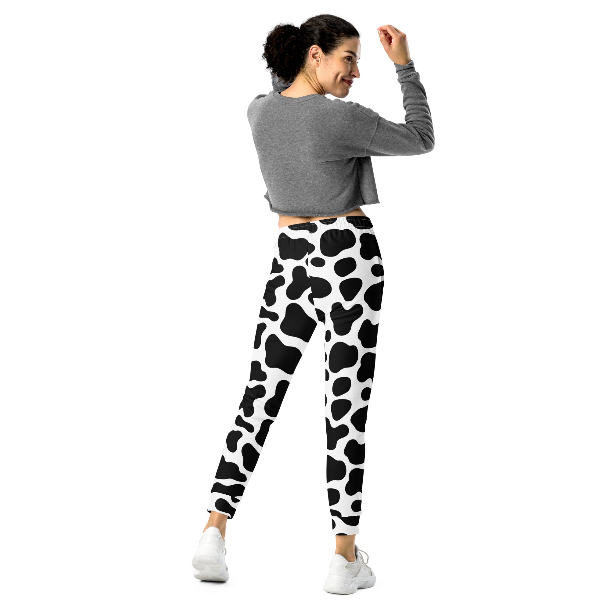 Women’s black and white cow print recycled jogger pants with cozy brushed fleece and pockets shown from the front