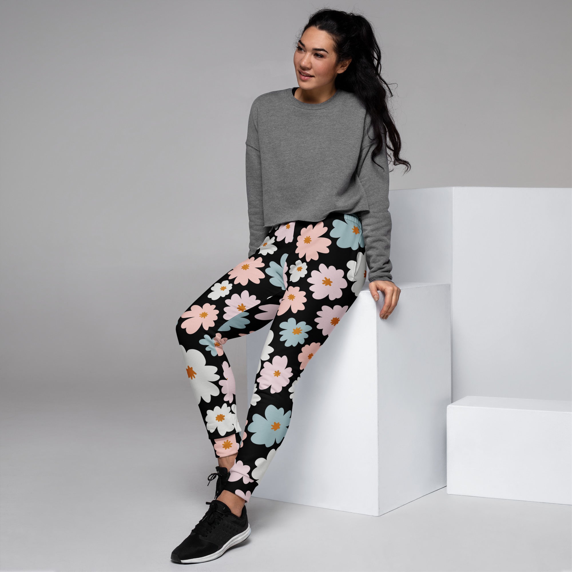 Women’s retro floral recycled jogger pants with pockets in black featuring vibrant pink white and light blue daisy pattern