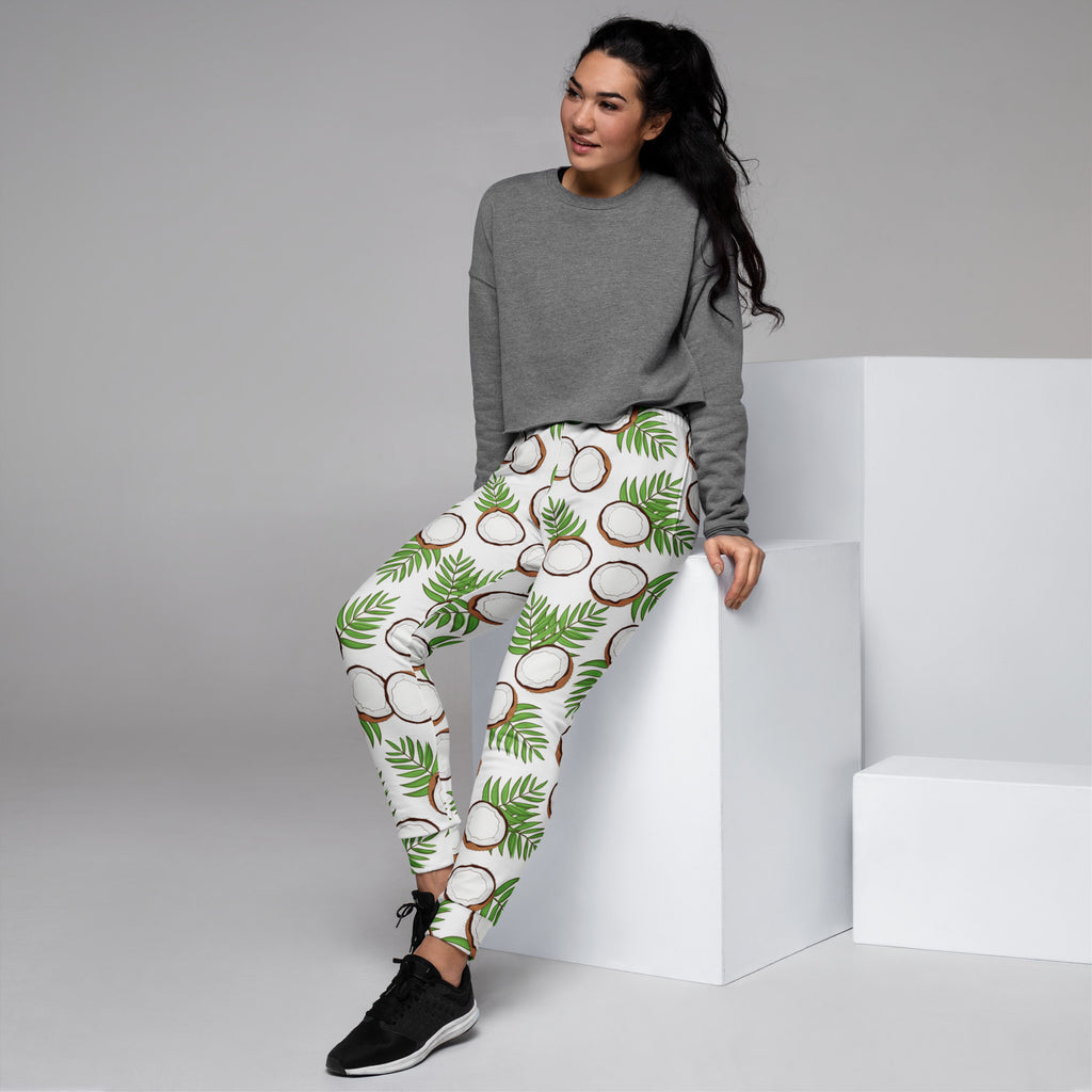 White recycled jogger pants with cozy fleece inside featuring vibrant coconut and green palm leaf pattern and pockets