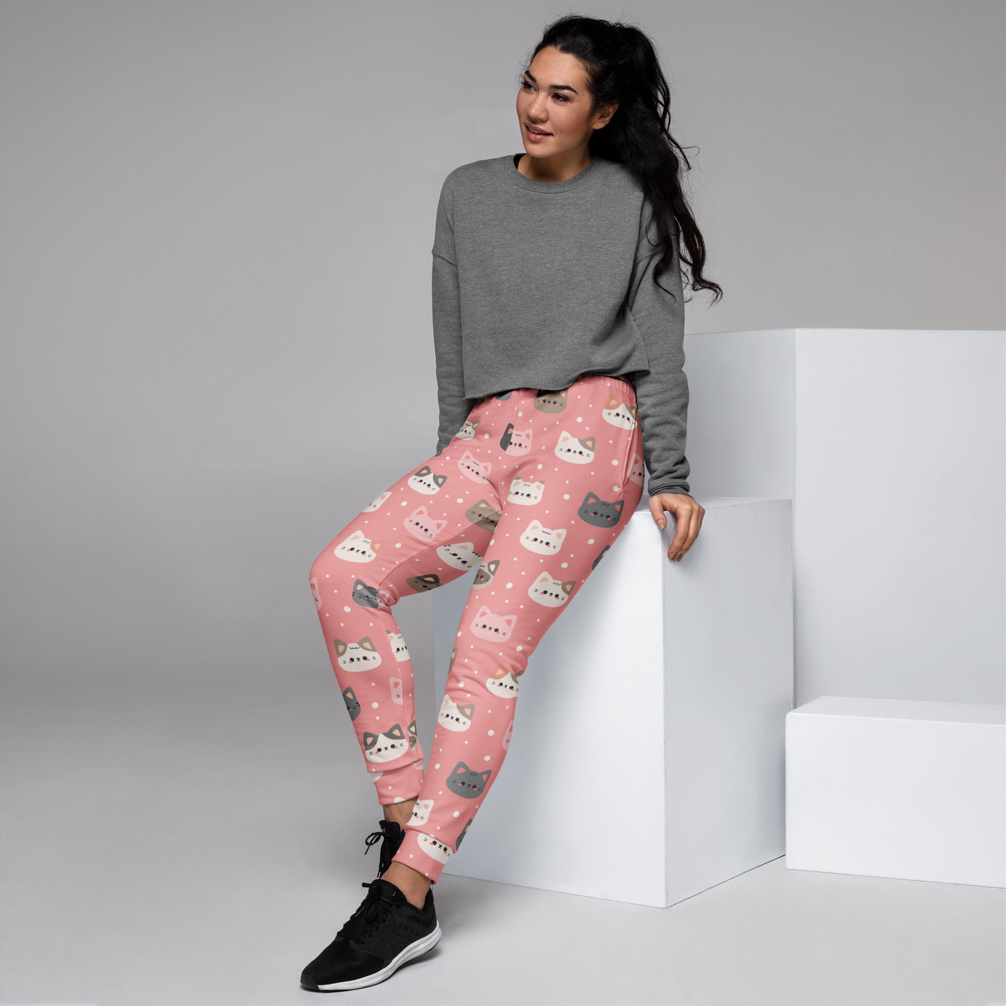 Women’s pink recycled jogger pants with cozy fleece inside featuring playful white and gray cartoon cat faces and polka dots