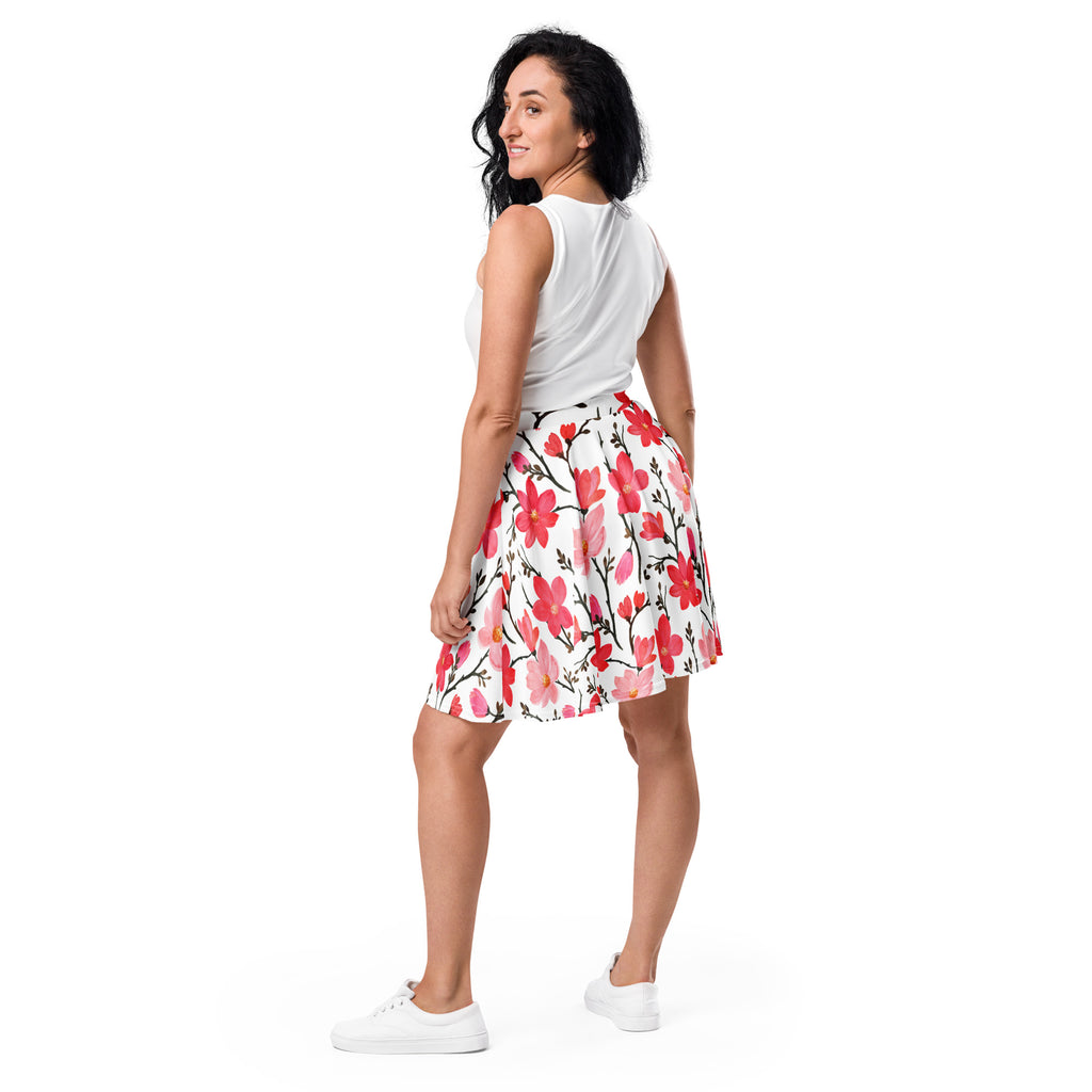 A white pleated womens skater skirt with vibrant pink and red floral pattern on black stems made from recycled fabric