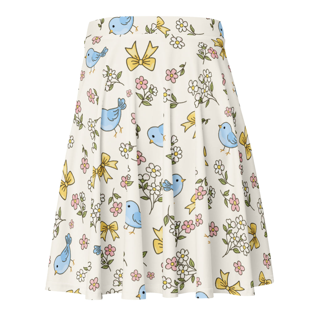 Women’s blue bird skater skirt in cream pleated fabric with light blue birds yellow bows and pink white flowers