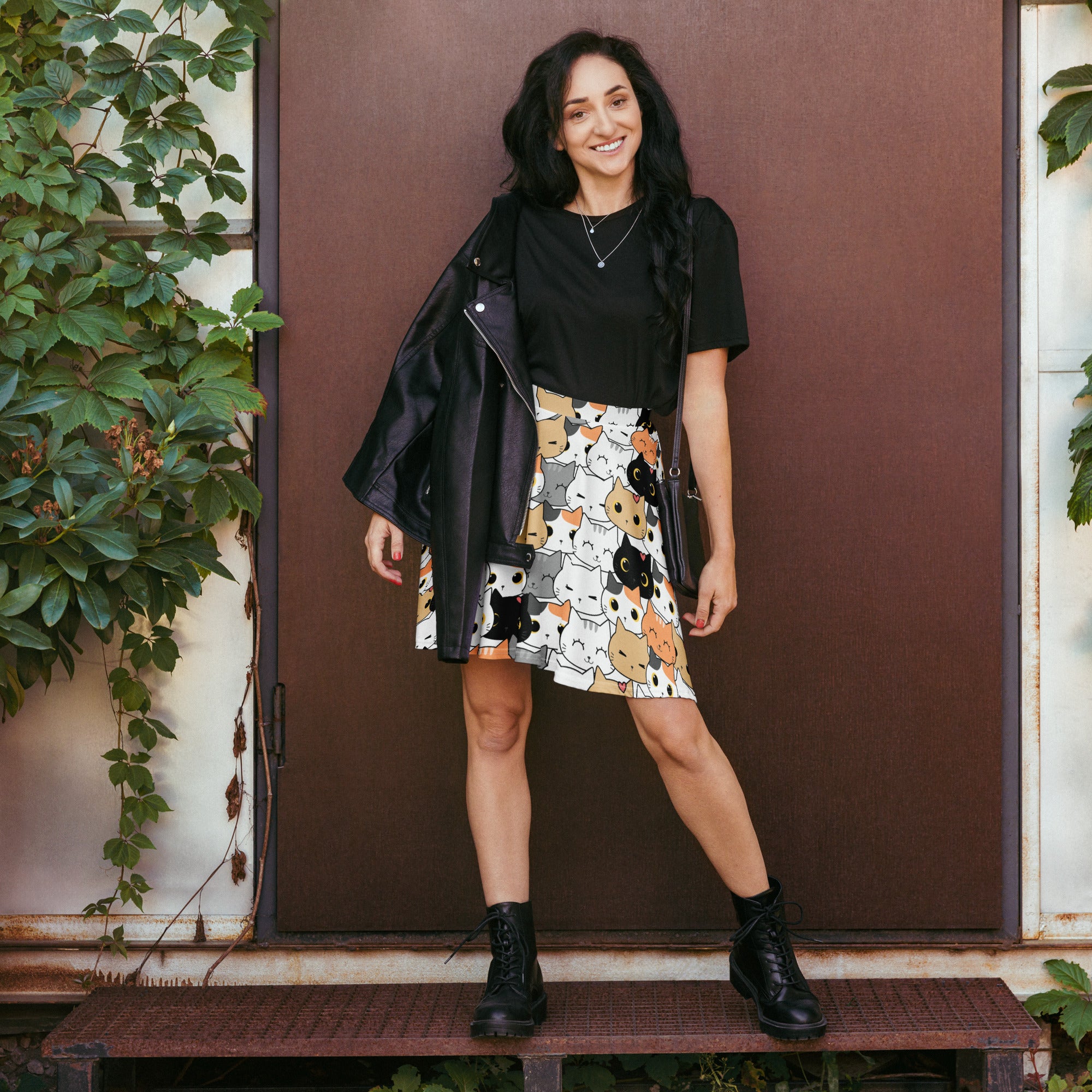 A black leather jacket with zipper detail worn over a black top paired with women’s cat face skater skirt flowy high waisted with upf 50 and recycled fabric