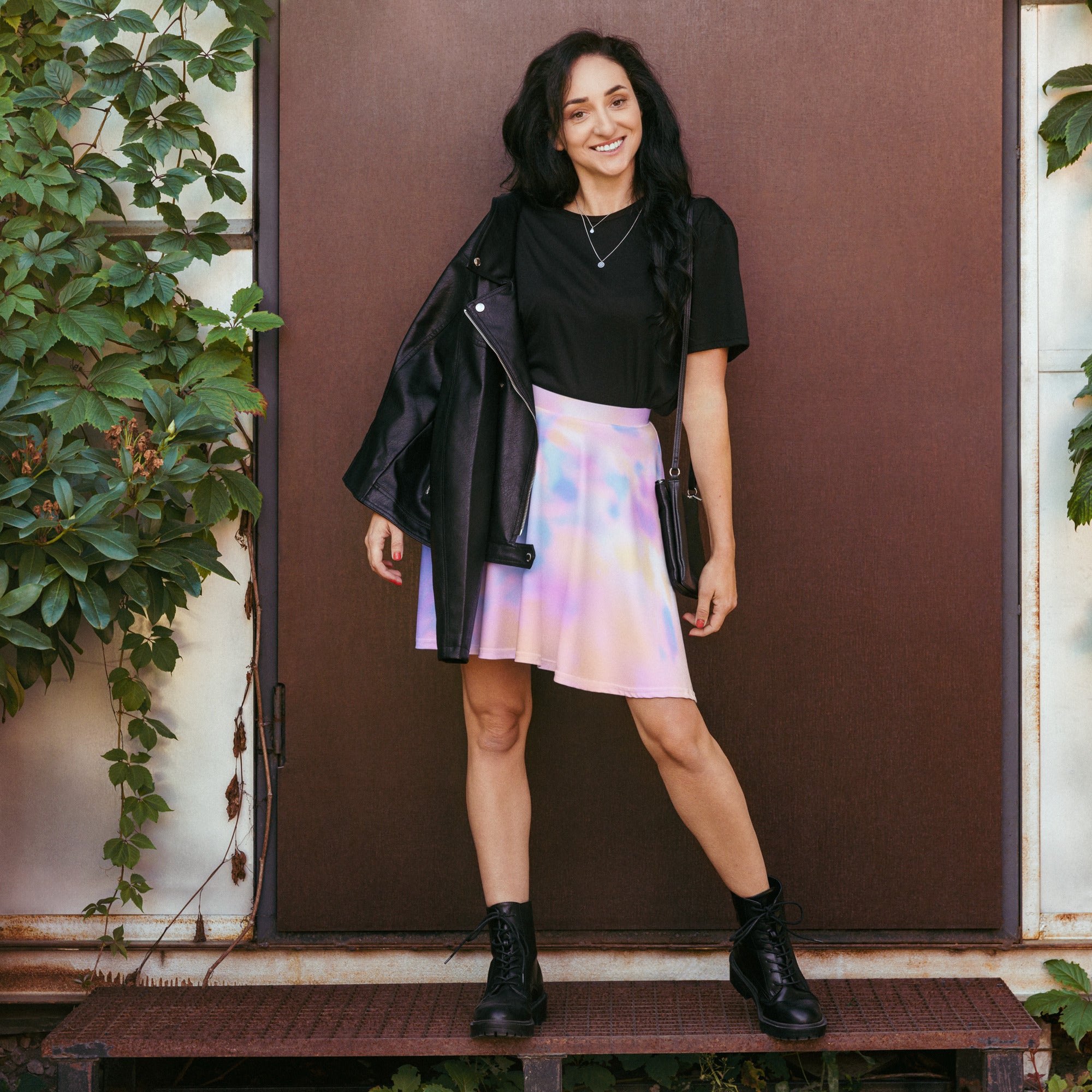 A black leather jacket with glossy finish and silver zippers paired with women’s pastel watercolor tie dye skater skirt