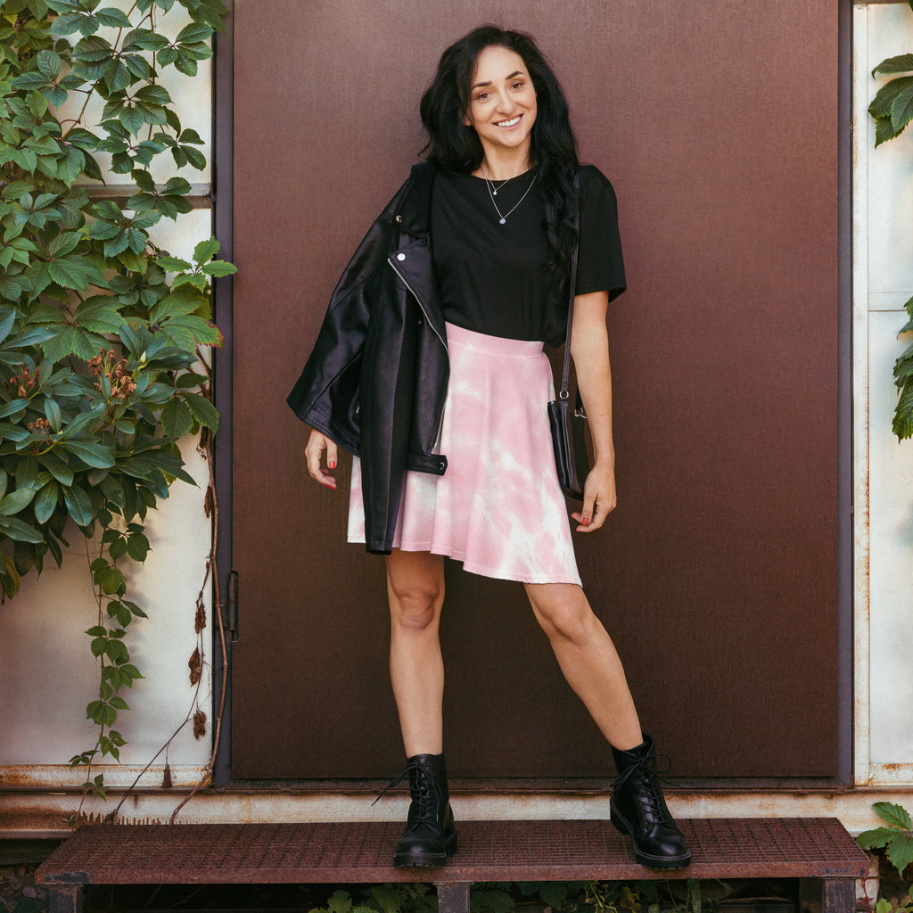 Black leather moto jacket with silver zipper and button details paired with women’s pink tie dye skater skirt