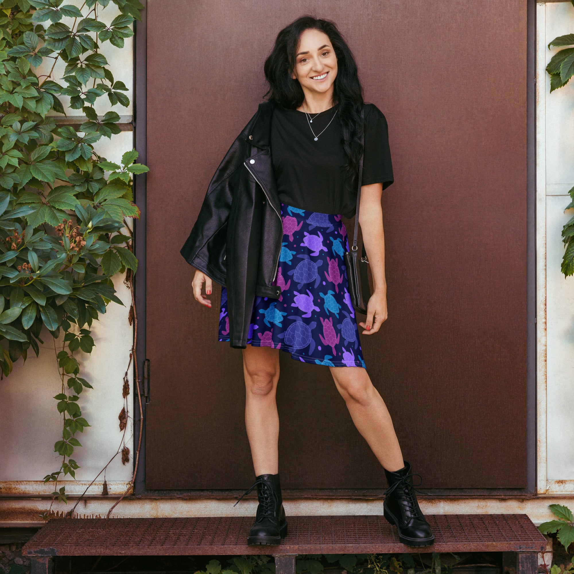 A black leather jacket with zipper detail worn over a women’s purple sea turtle skater skirt with upf 50 and recycled fabric