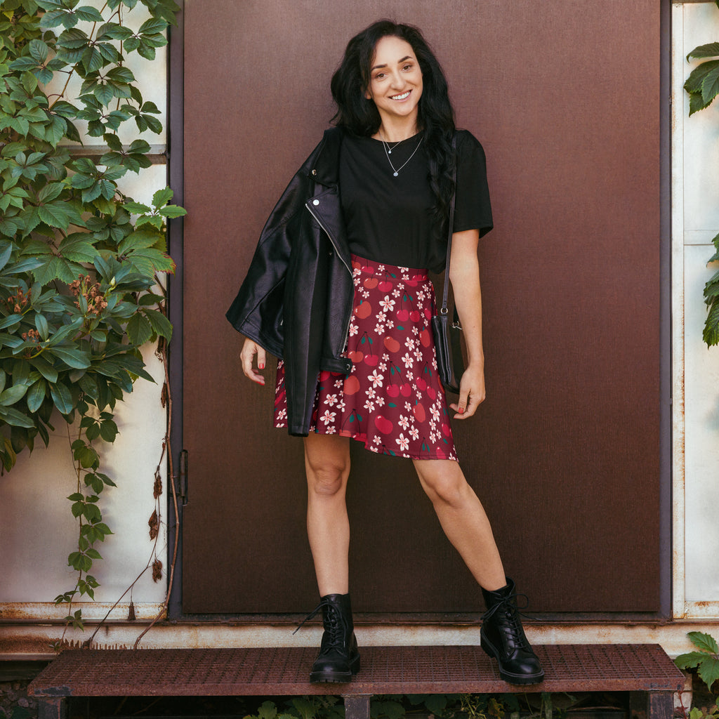 A woman wearing a women’s burgundy cherry blossom skater skirt with UPF 50 plus recycled fabric with black top and boots