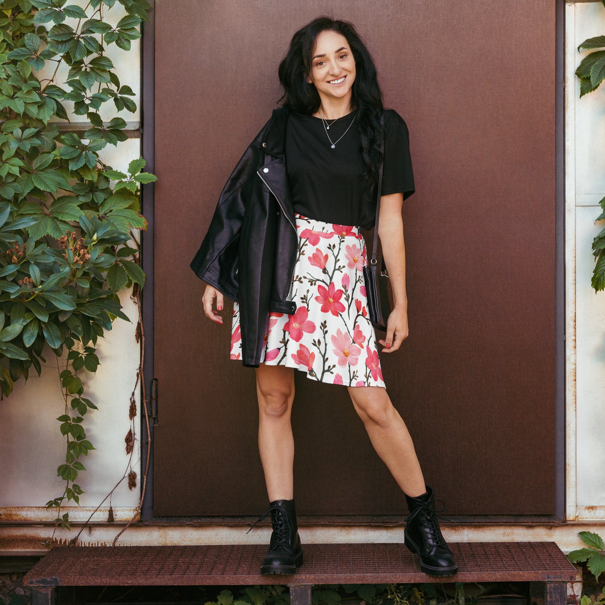 Black leather jacket with zipper detail and shoulder pads paired with women’s pink watercolor floral skater skirt