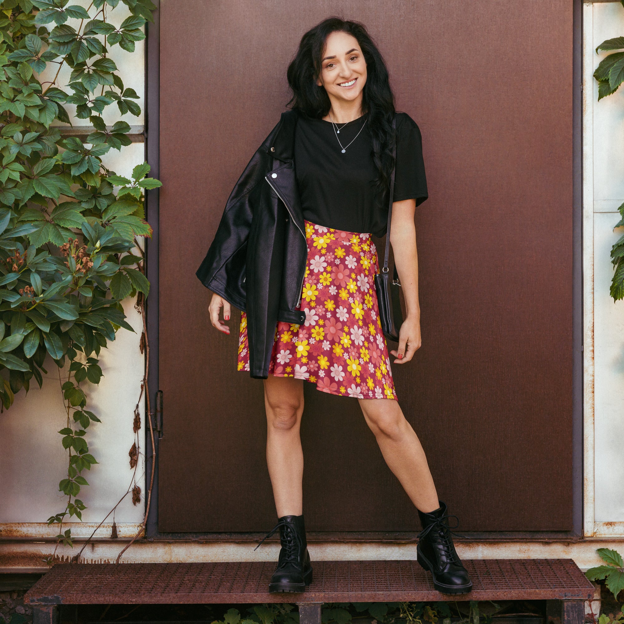 A woman wearing a black leather jacket over a women’s red retro floral skater skirt with flowy high waisted recycled fabric