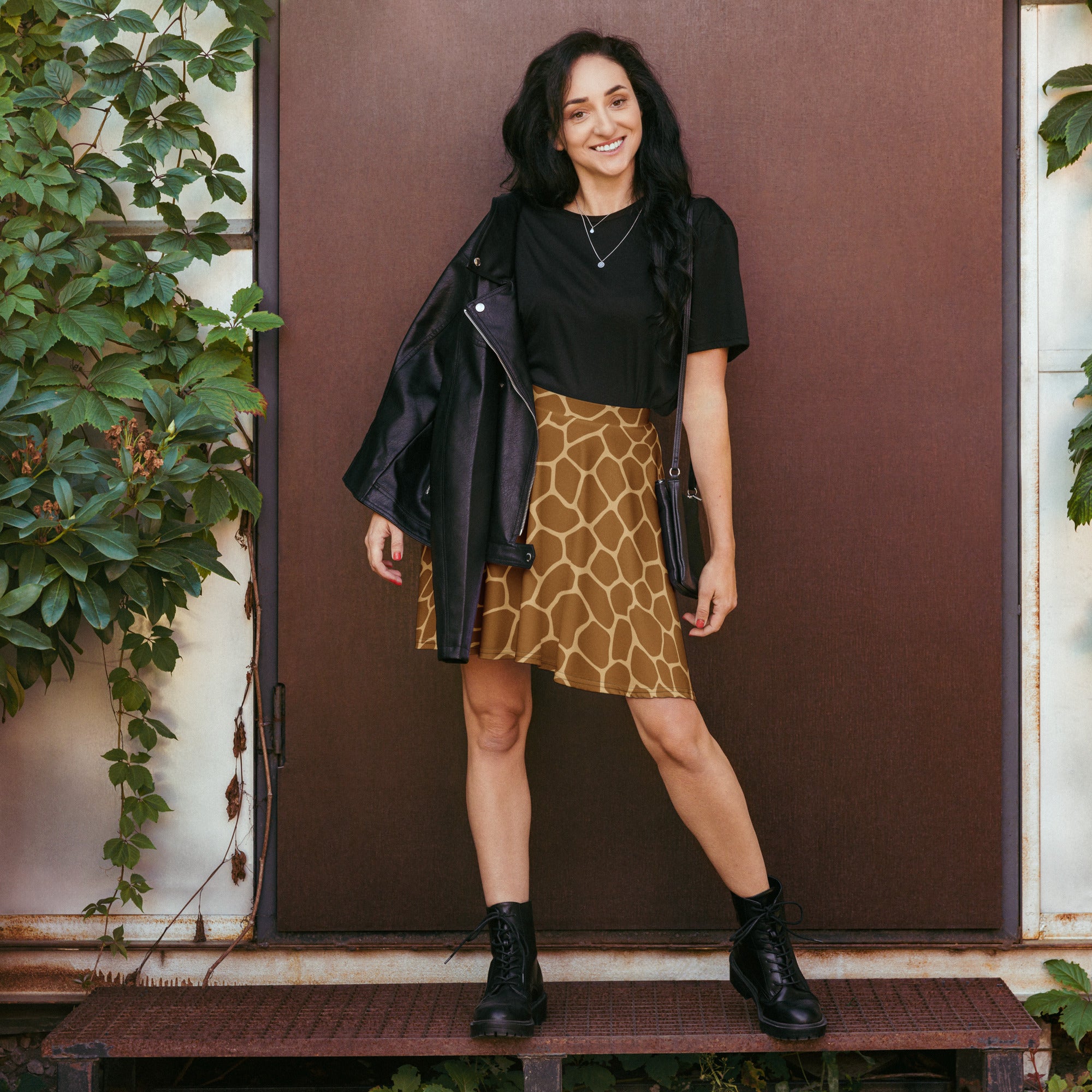 Women’s black leather jacket with zipper detail and shoulder pads paired with giraffe print skater skirt with upf 50+