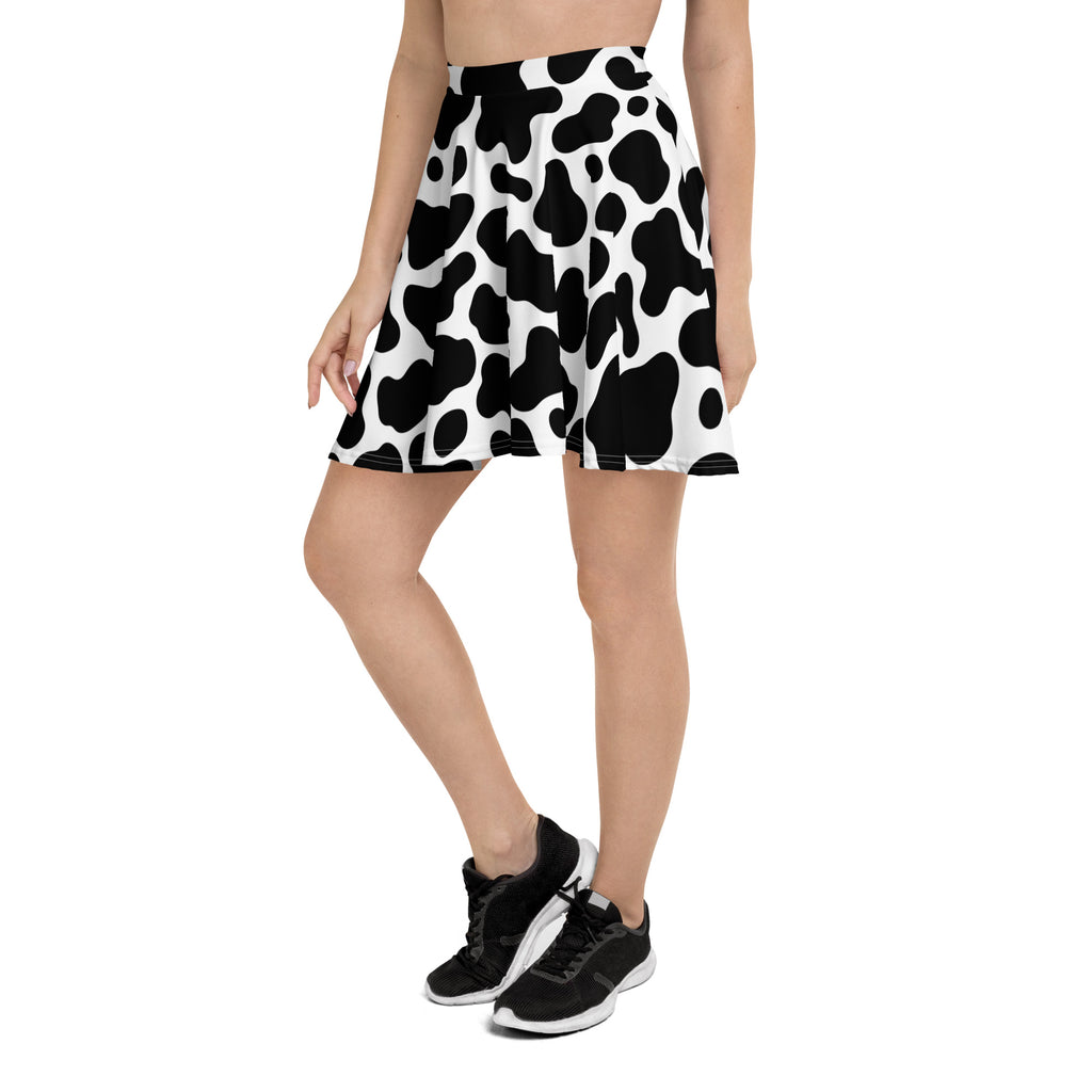 A flowy high waisted women’s skater skirt with a black and white cow print made from recycled fabric with upf 50+