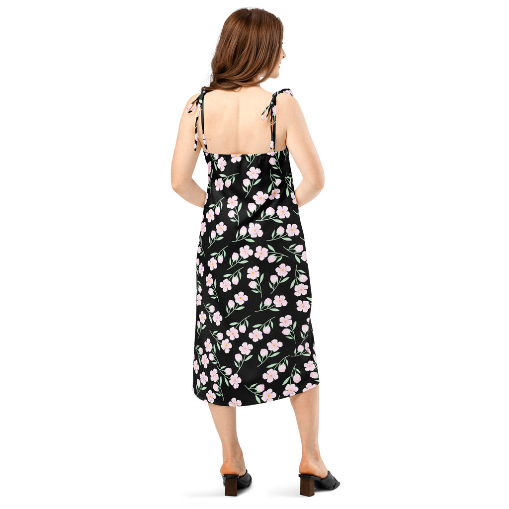 Women’s black floral slip midi dress with delicate pink blossoms and green stems featuring adjustable tie-back straps