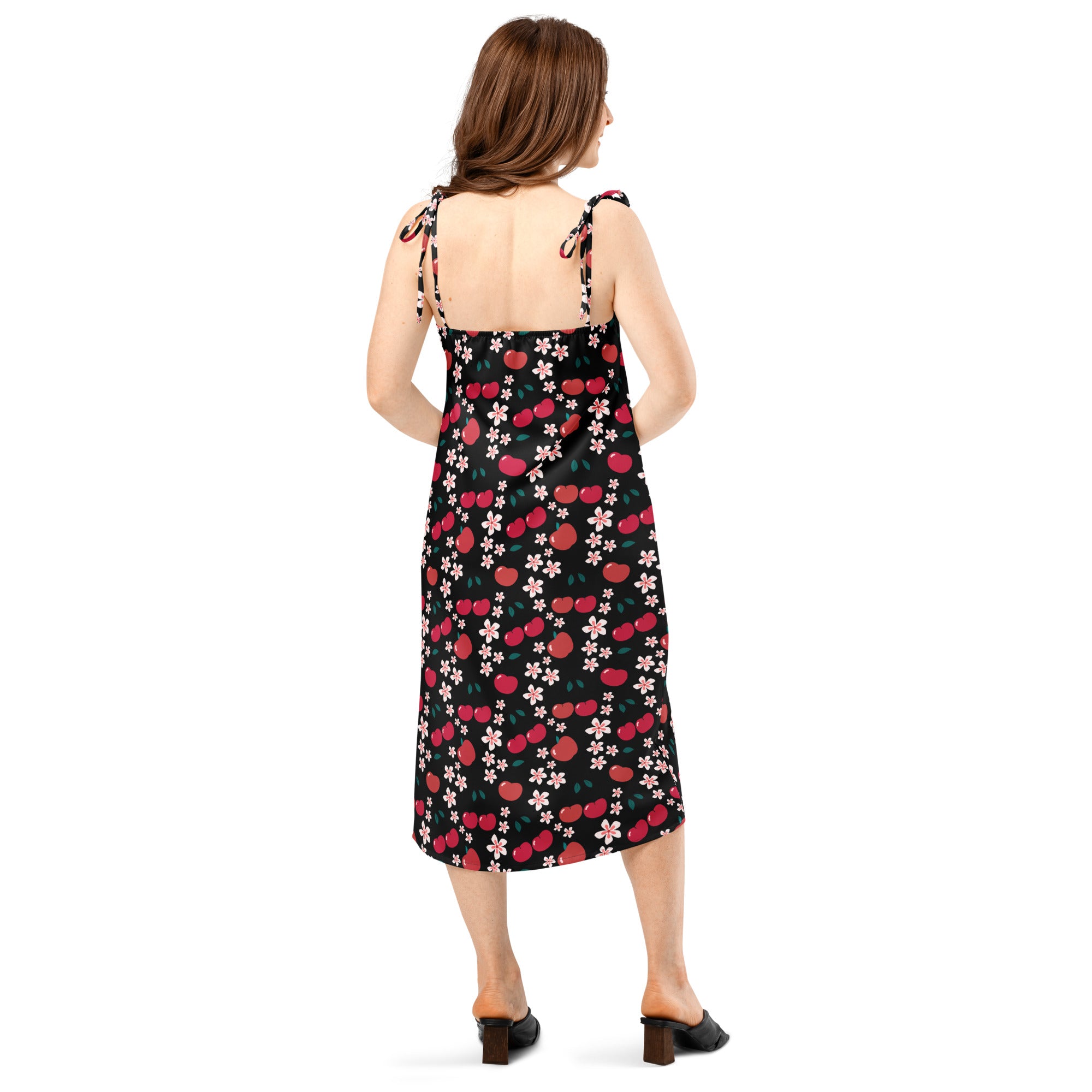 Black midi slip dress with red cherries pink flowers print flowing fabric and adjustable tie-back straps shown from back
