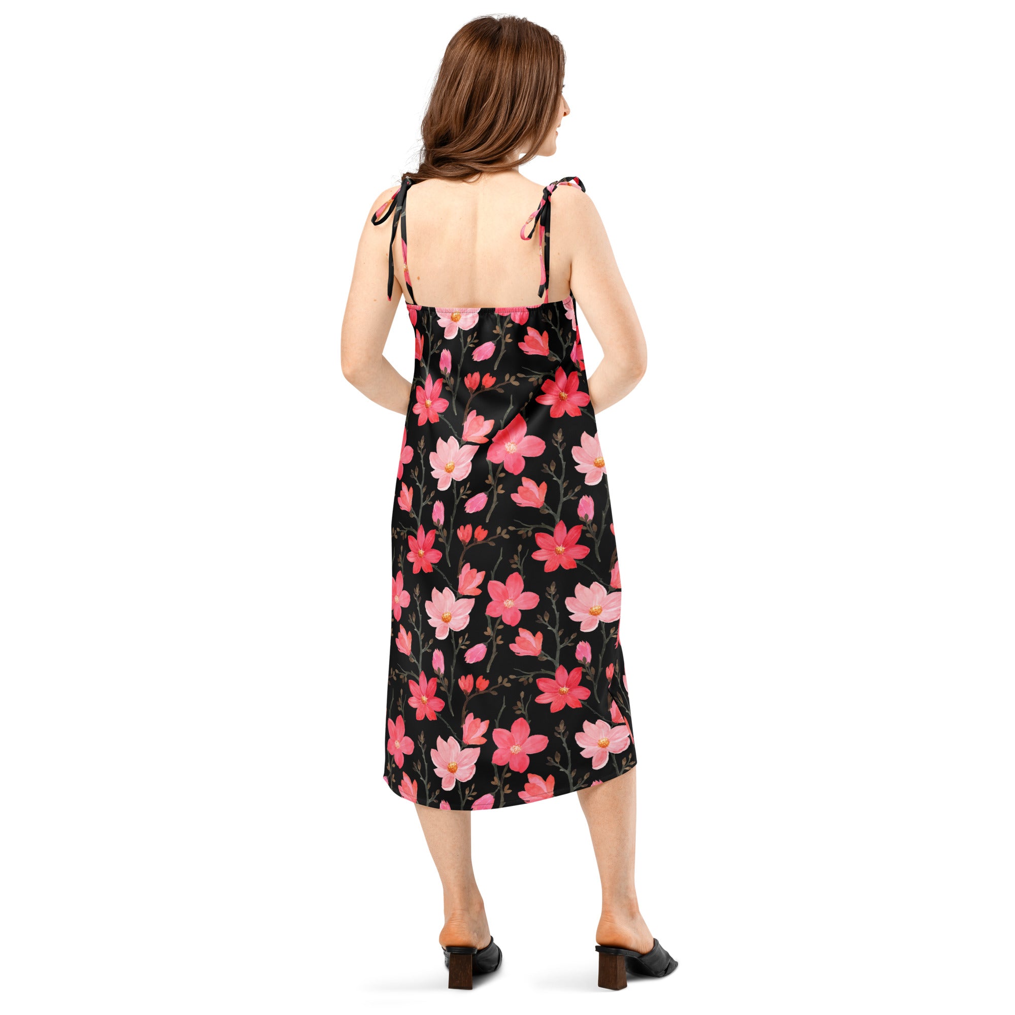 A black midi slip dress with a vibrant pink blossom floral pattern and delicate adjustable tie-back straps