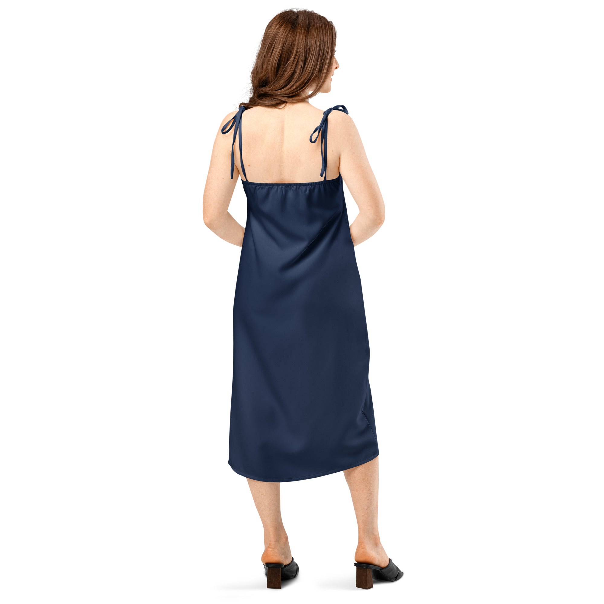 Women's navy slip midi dress with adjustable tie straps; back view on model wearing sandals in soft satin-like fabric.