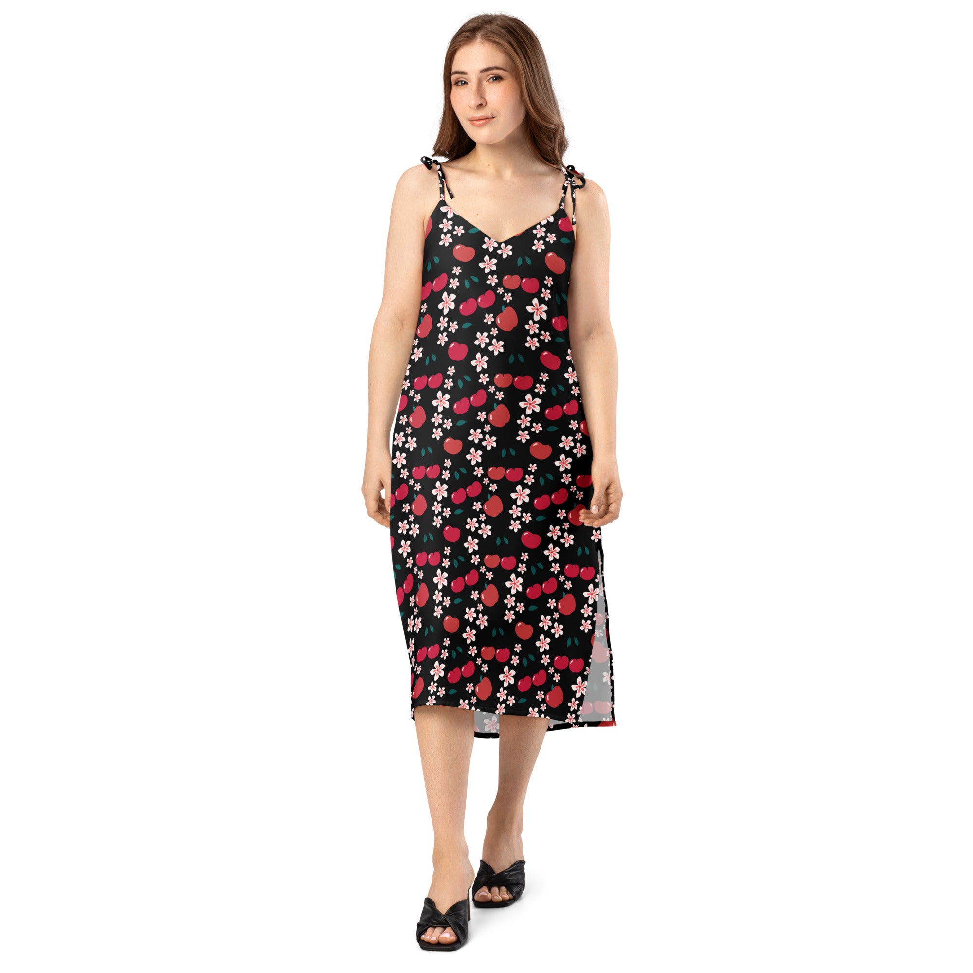 A black sleeveless midi slip dress with red cherry and pink blossom pattern and adjustable tied shoulder straps