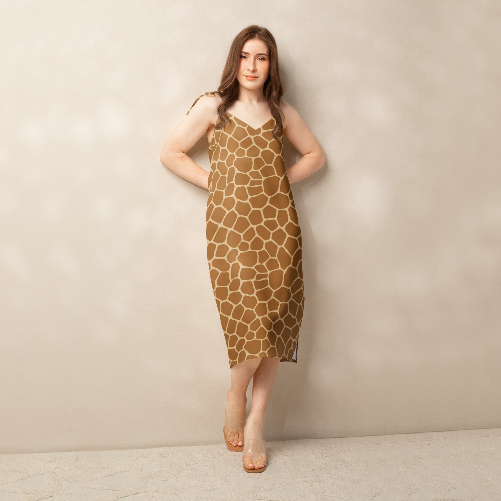 A woman wears a women’s giraffe print slip dress with adjustable tie straps and built in bra in tan and beige